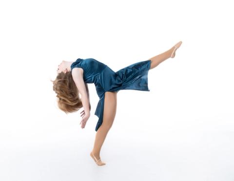 A dancer balances on one hand with a leg extended