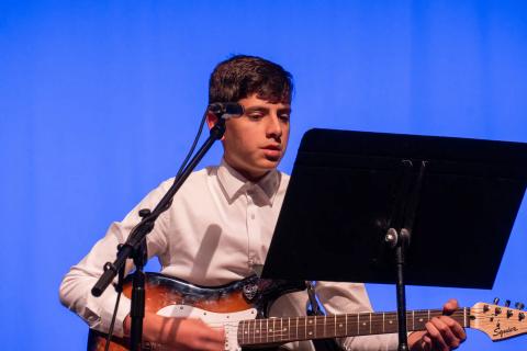A musician sings and plays guitar on stage