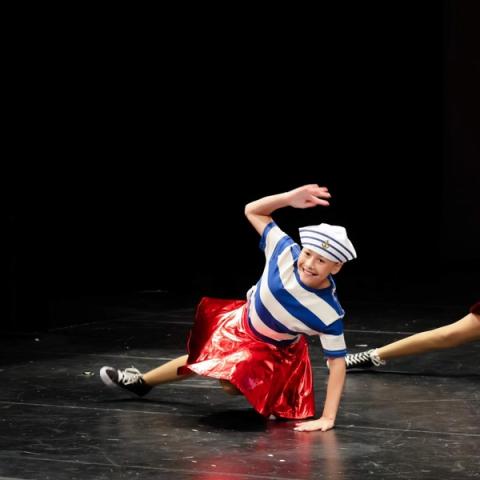 A dancer performs on stage in a red and blue costume