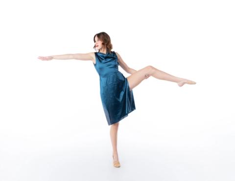 A dancer extends one leg in a teal costume