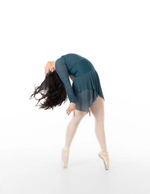 A dancer bends forward in a teal costume