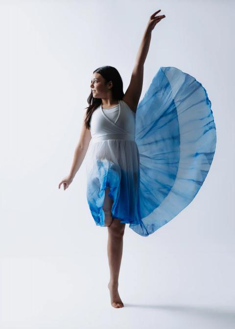 A dancer in a blue costume poses in the studio