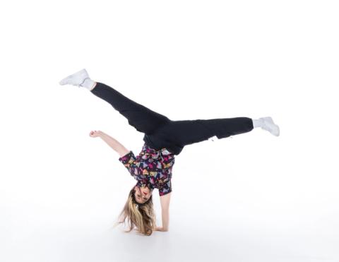 A dancer balances upside down with legs extended