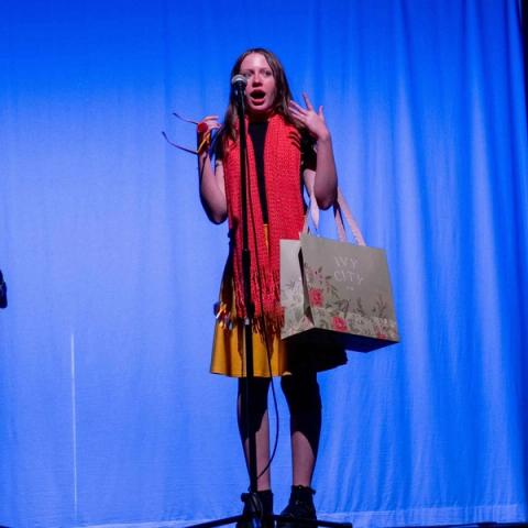 A performer sings into a microphone on stage