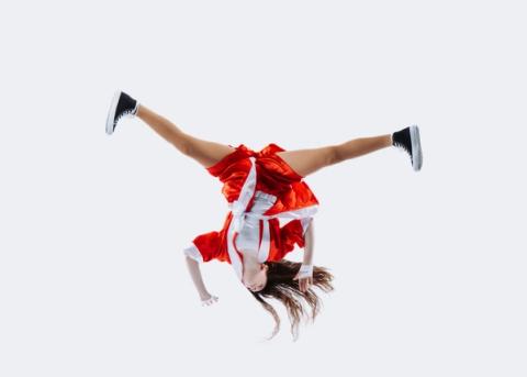 A dancer performs an acrobatic move in a red costume