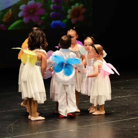 Young performers dance together on stage