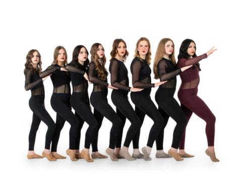A group of dancers pose together in black costumes