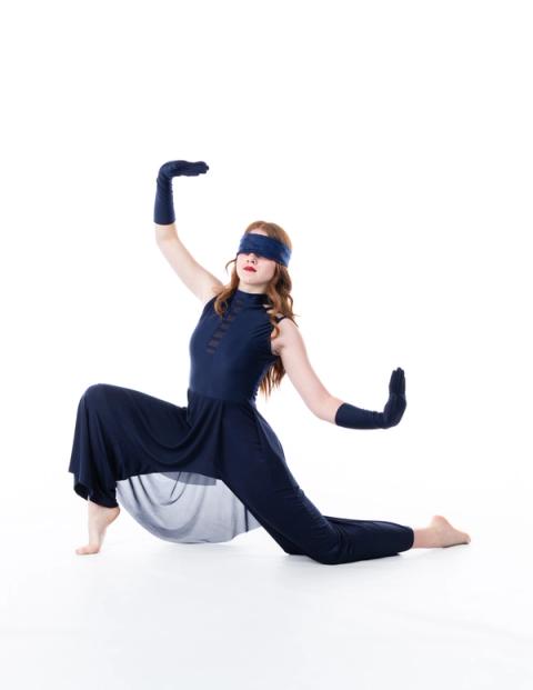 A dancer poses on the floor in a blue costume