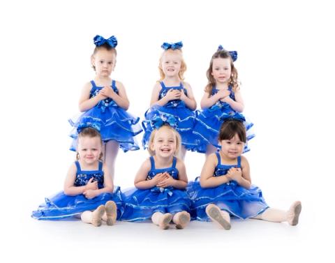 Young dancers pose together in blue costumes
