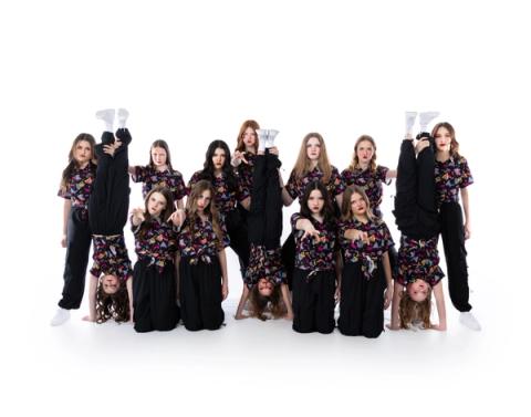 A large group of dancers pose in black costumes