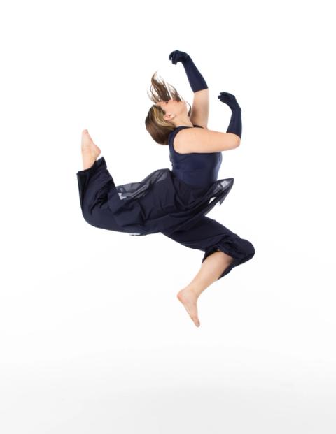 A dancer leaps in a navy costume