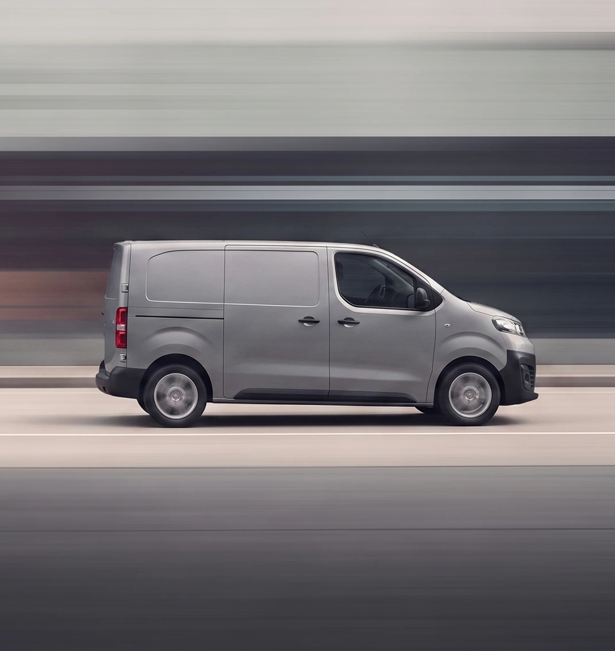 A grey delivery van driving past a motion-blurred background