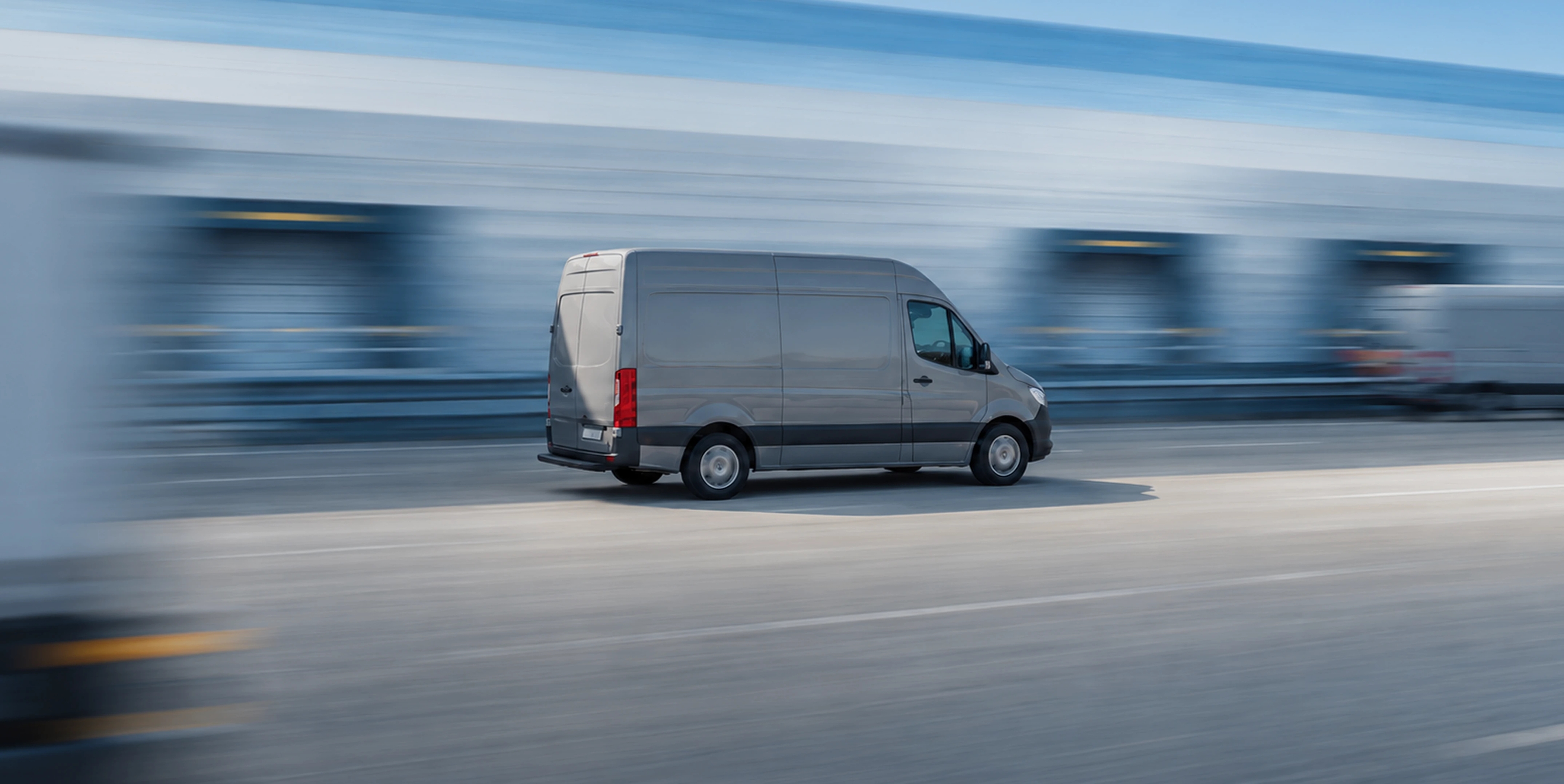 A grey delivery van at speed against a motion-blurred road