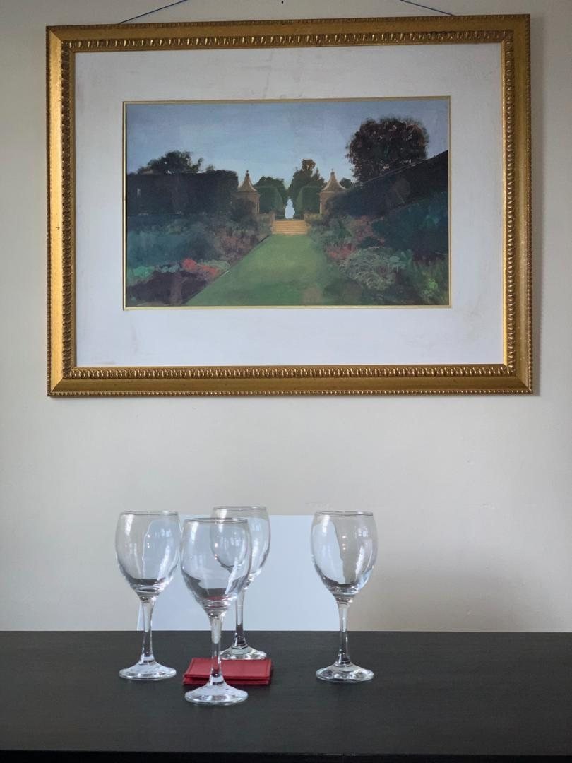 Dining table laid with glassware beneath framed art