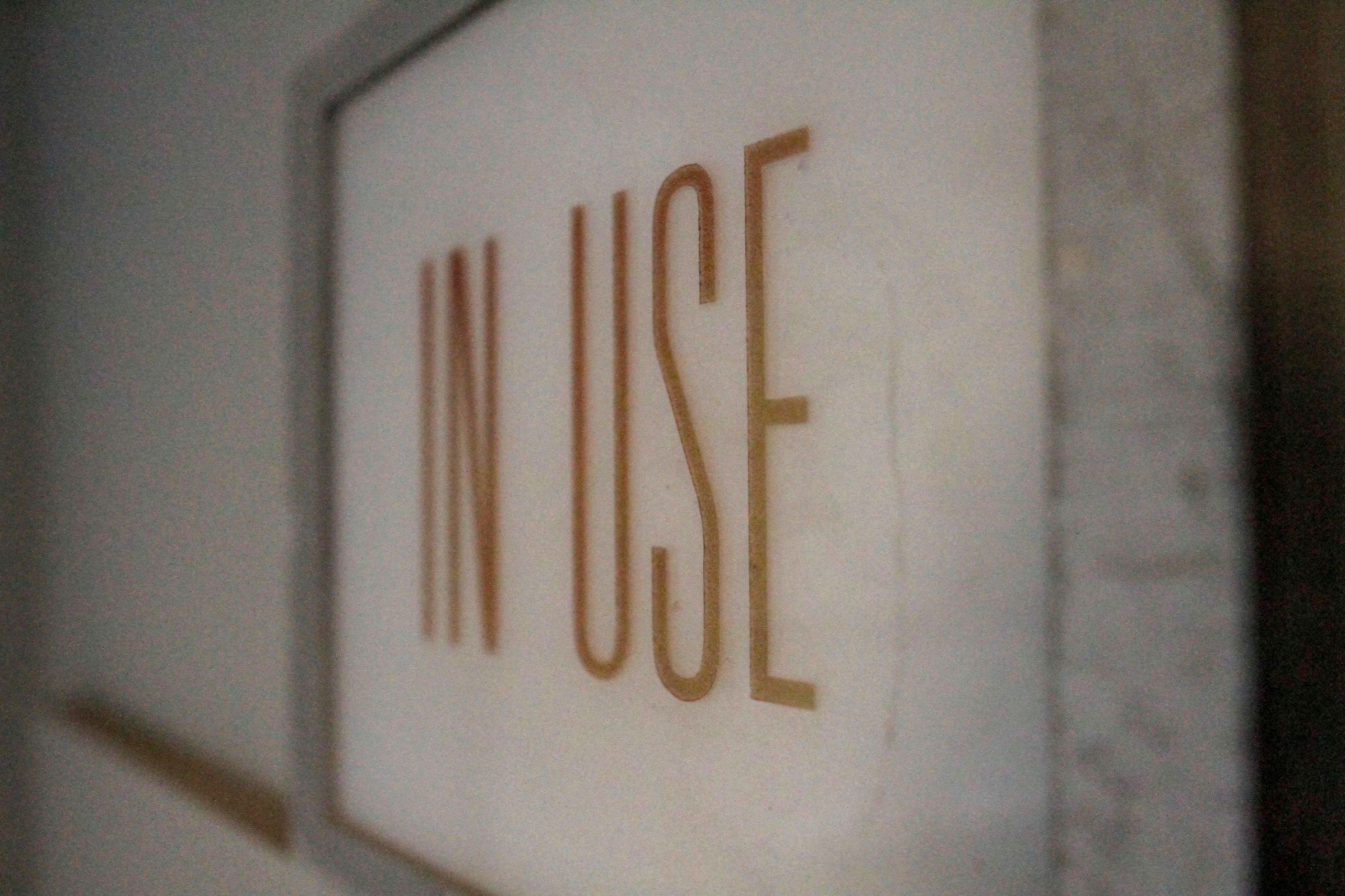 Vintage brass-lettered 'In Use' sign