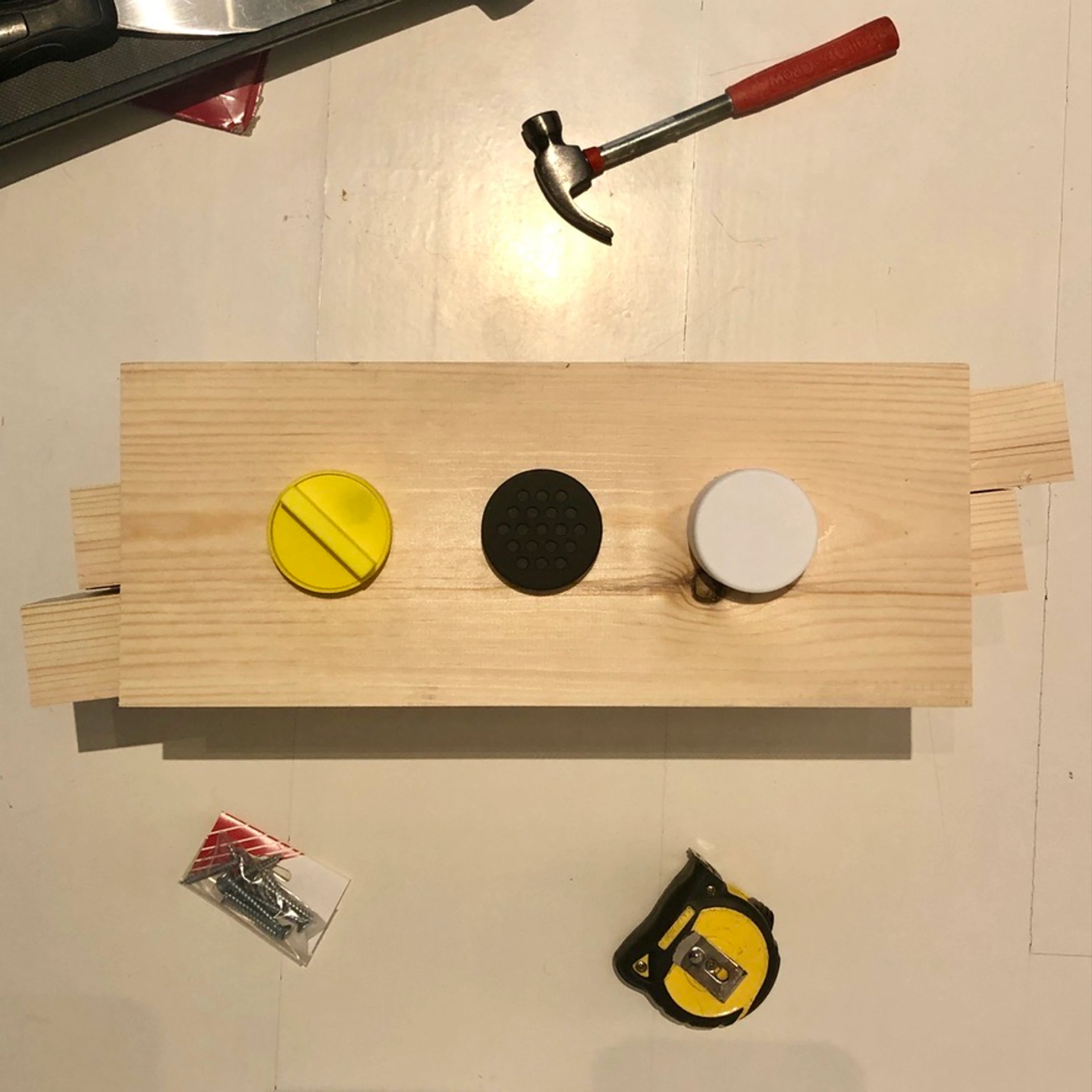 Three control caps set into a timber board, with the tools that cut it
