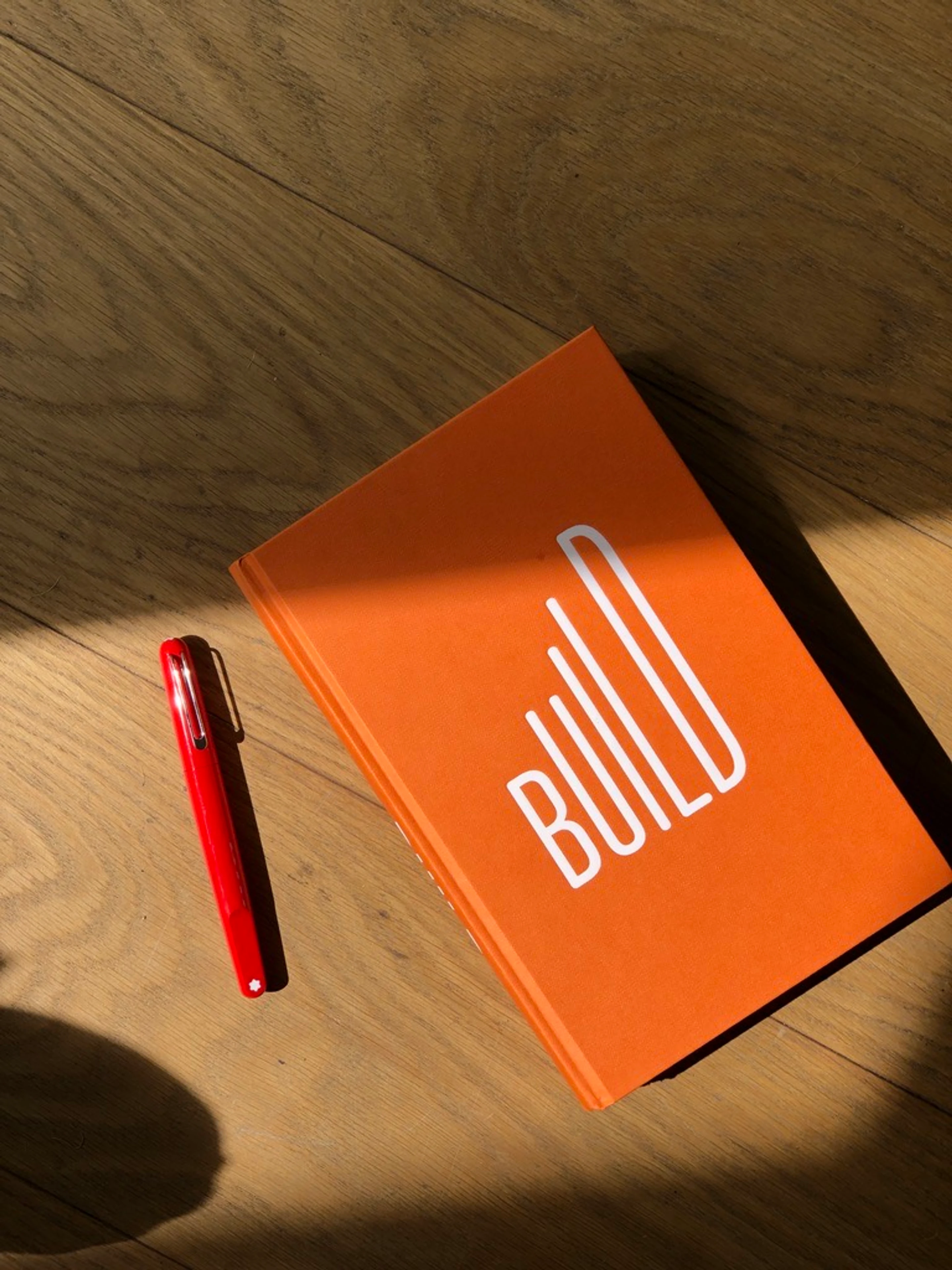 The BUILD book on a workshop floor, a pen beside it