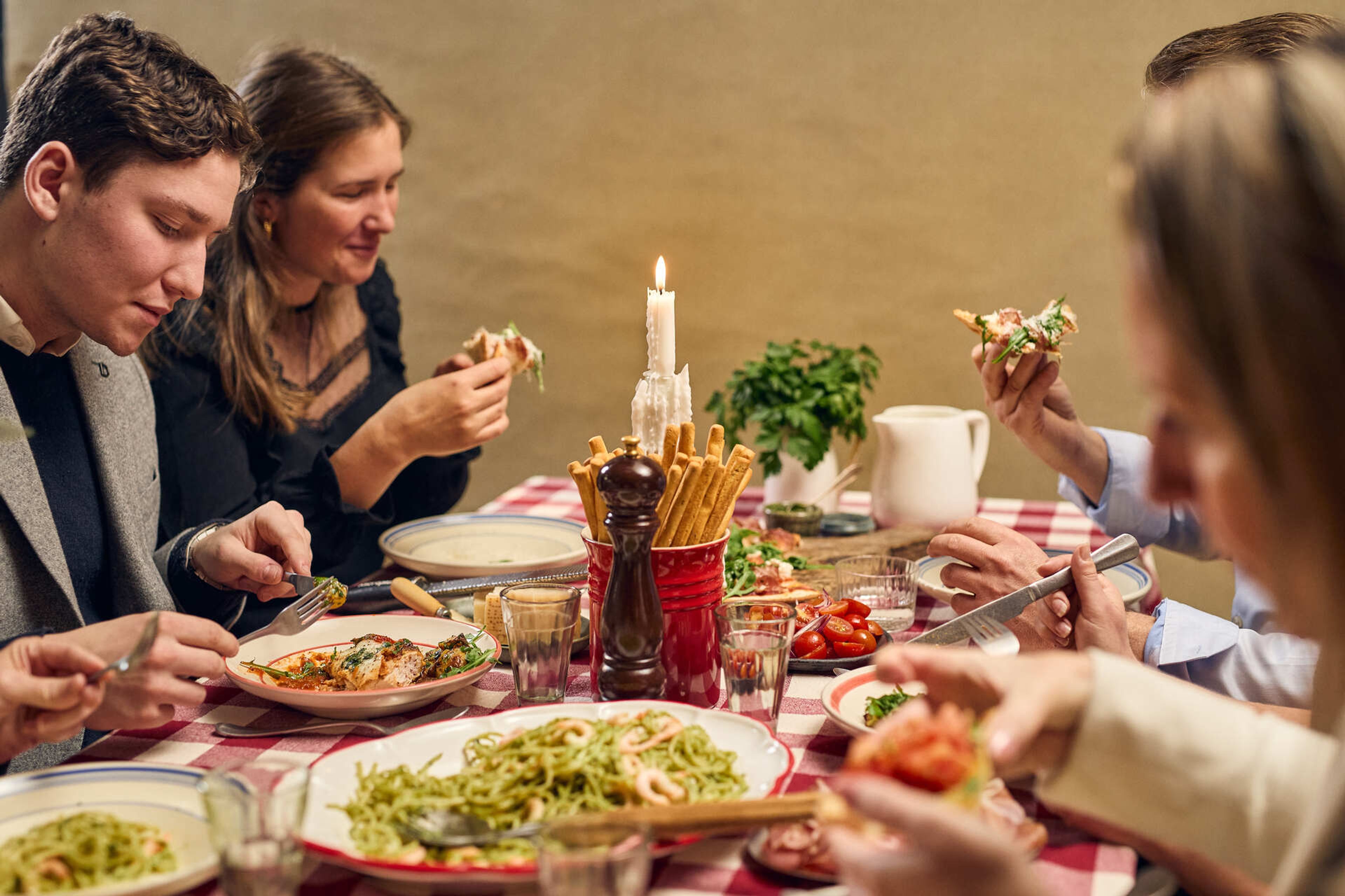 Et selskap spiser italiensk middag med pasta, brød og ost