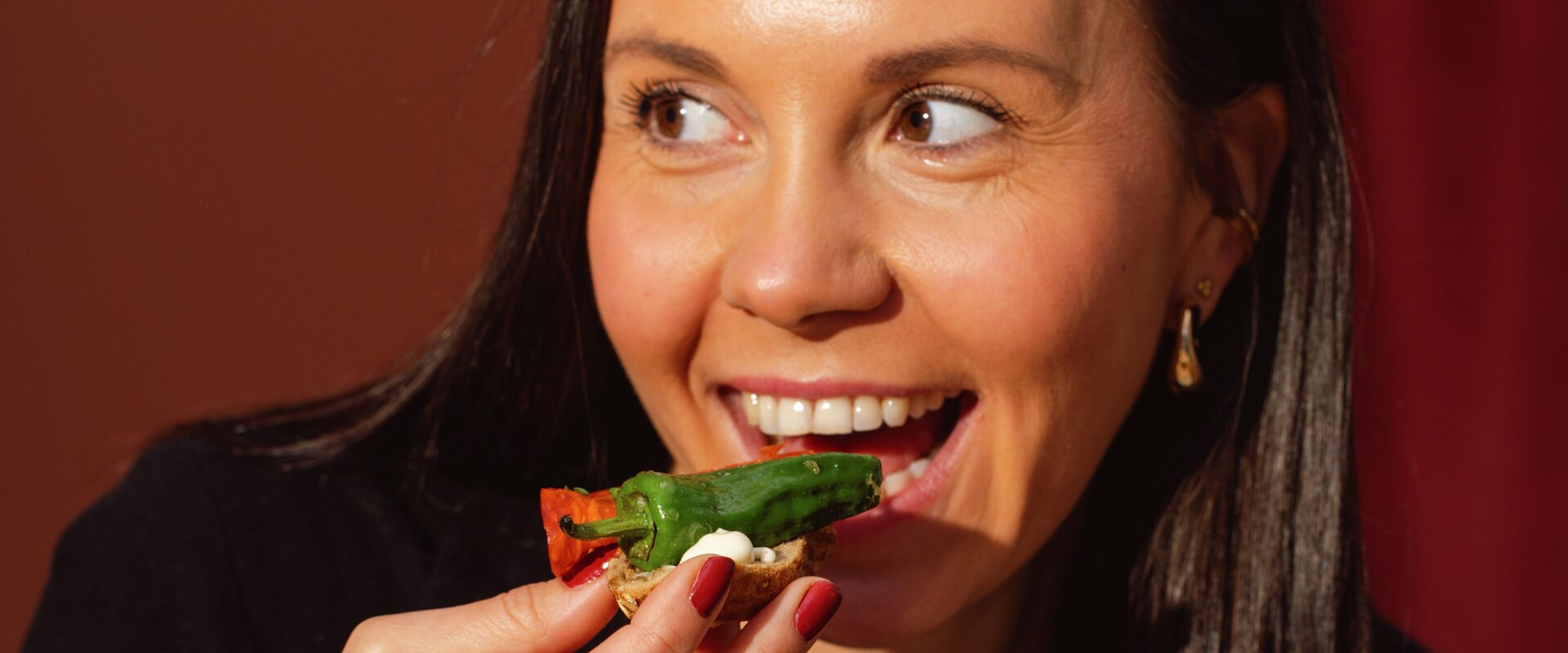 En kvinne med et stort smil spiser plukkmat.