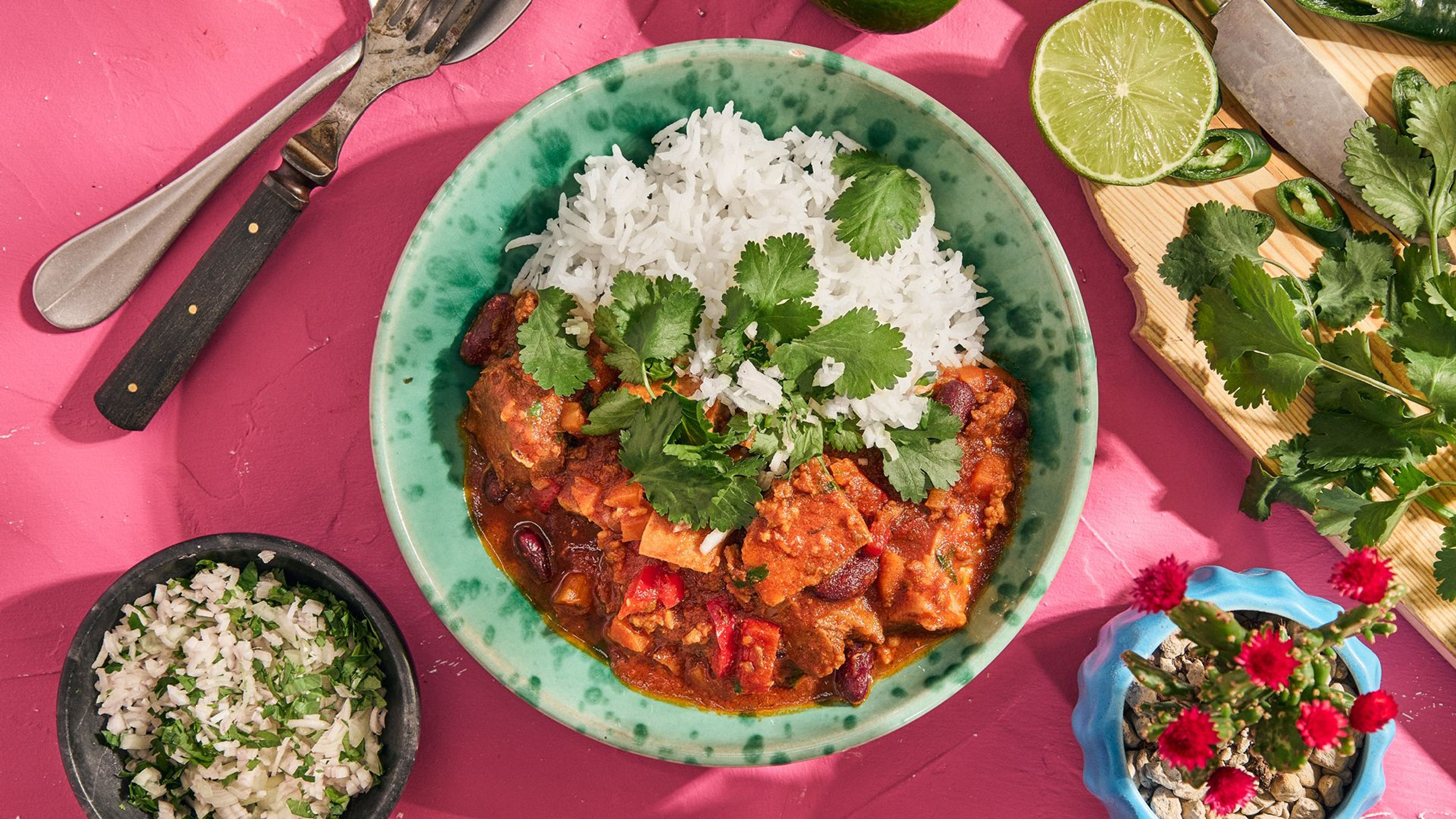 Mexicansk bønnegryte med svinebog og ris, pyntet med koriander. 