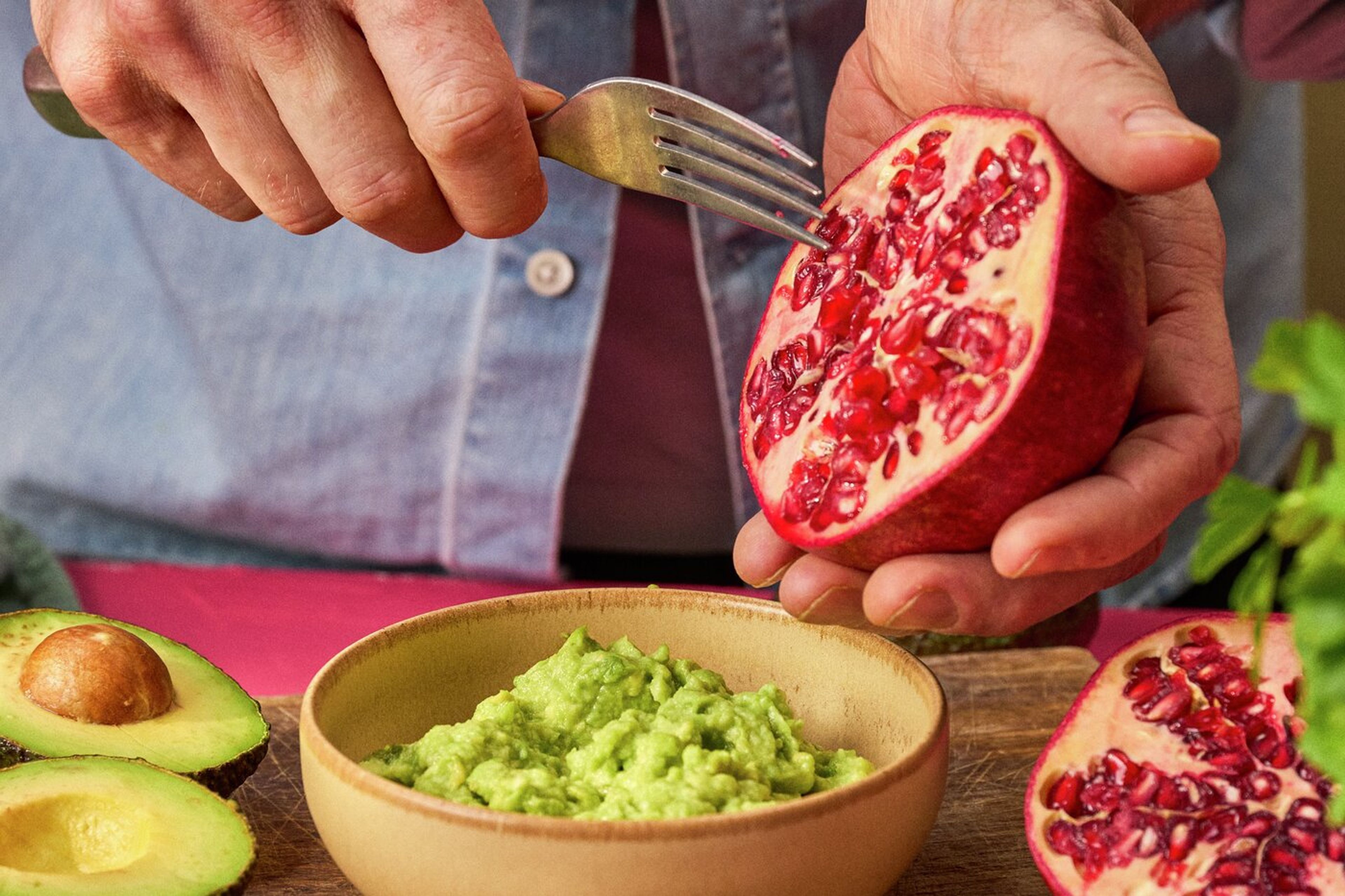 Skål med guacamole og gaffel som tar ut granateplekjerner.