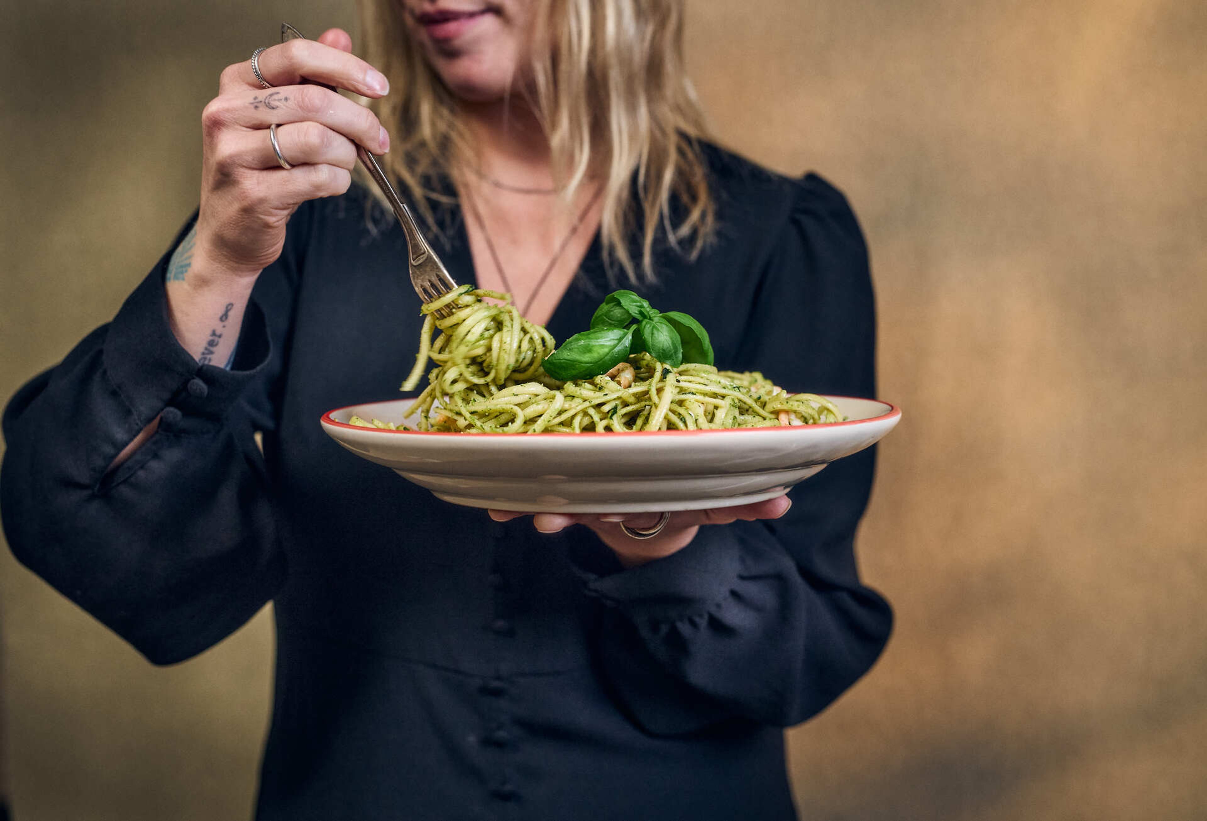 Kvinne snurrer pasta på en gaffel
