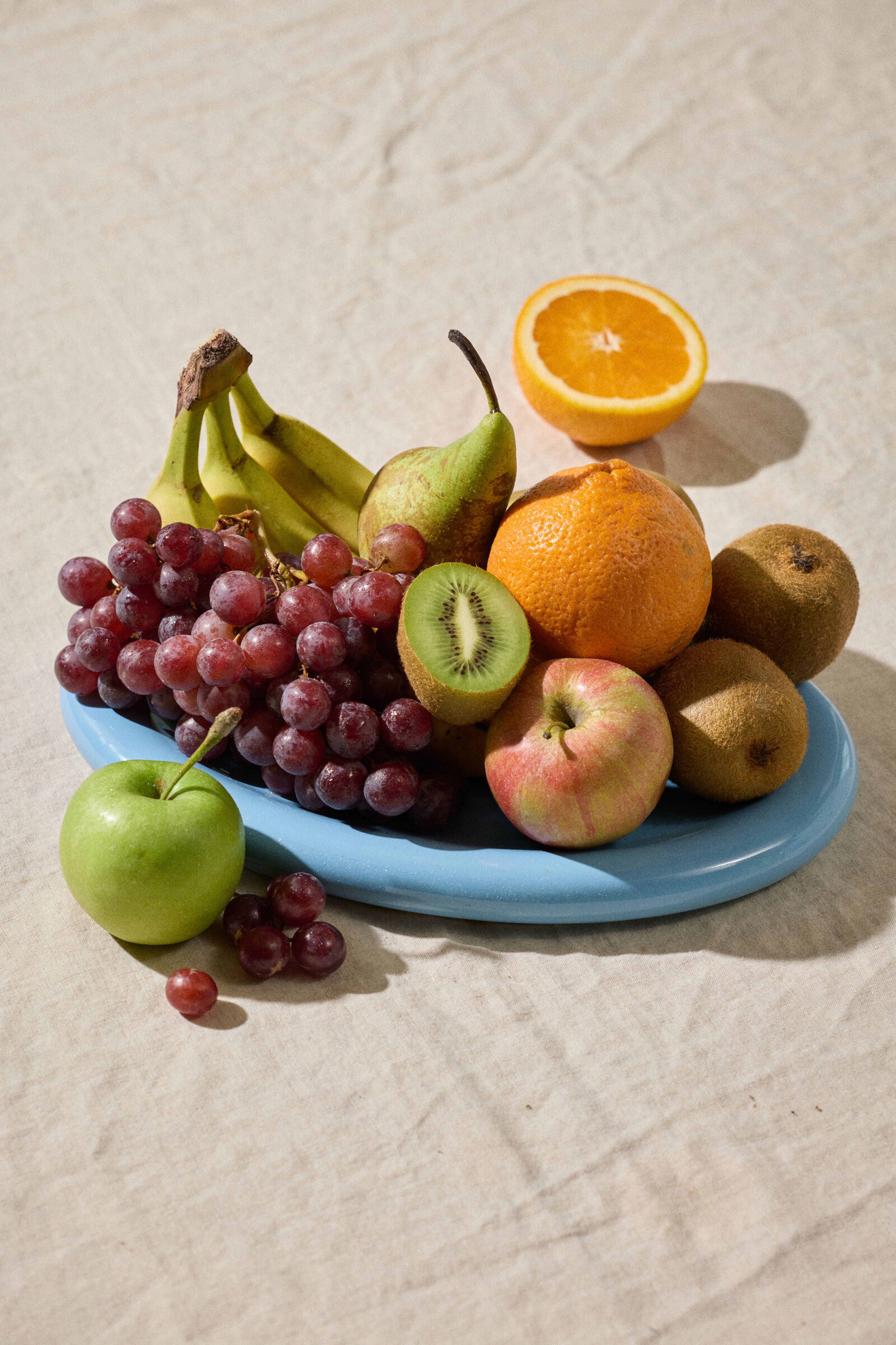 Fruktskål med druer, bananer, epler, pærer og appelsin.