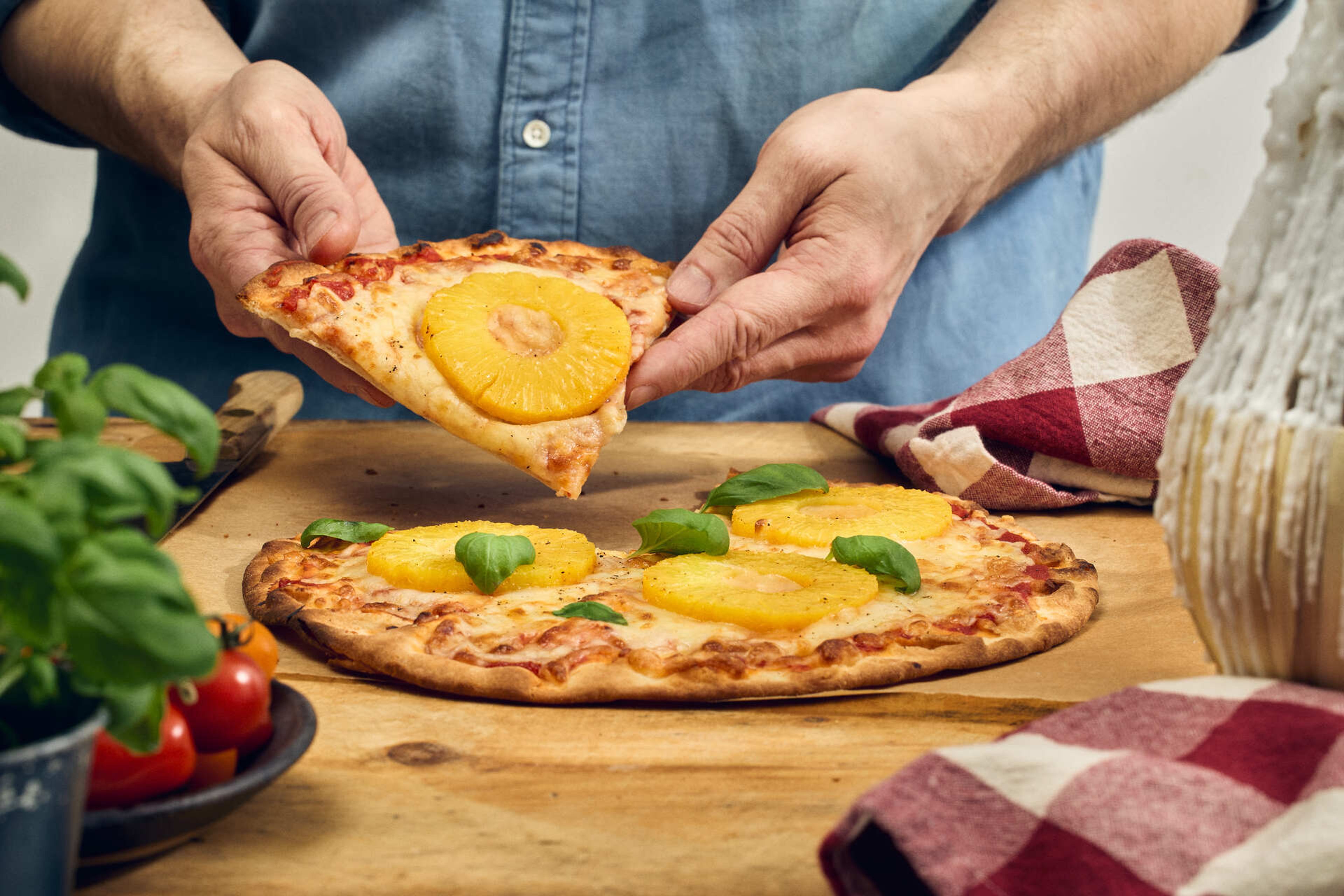 En hånd løfter et pizzastykke med italiensk topping