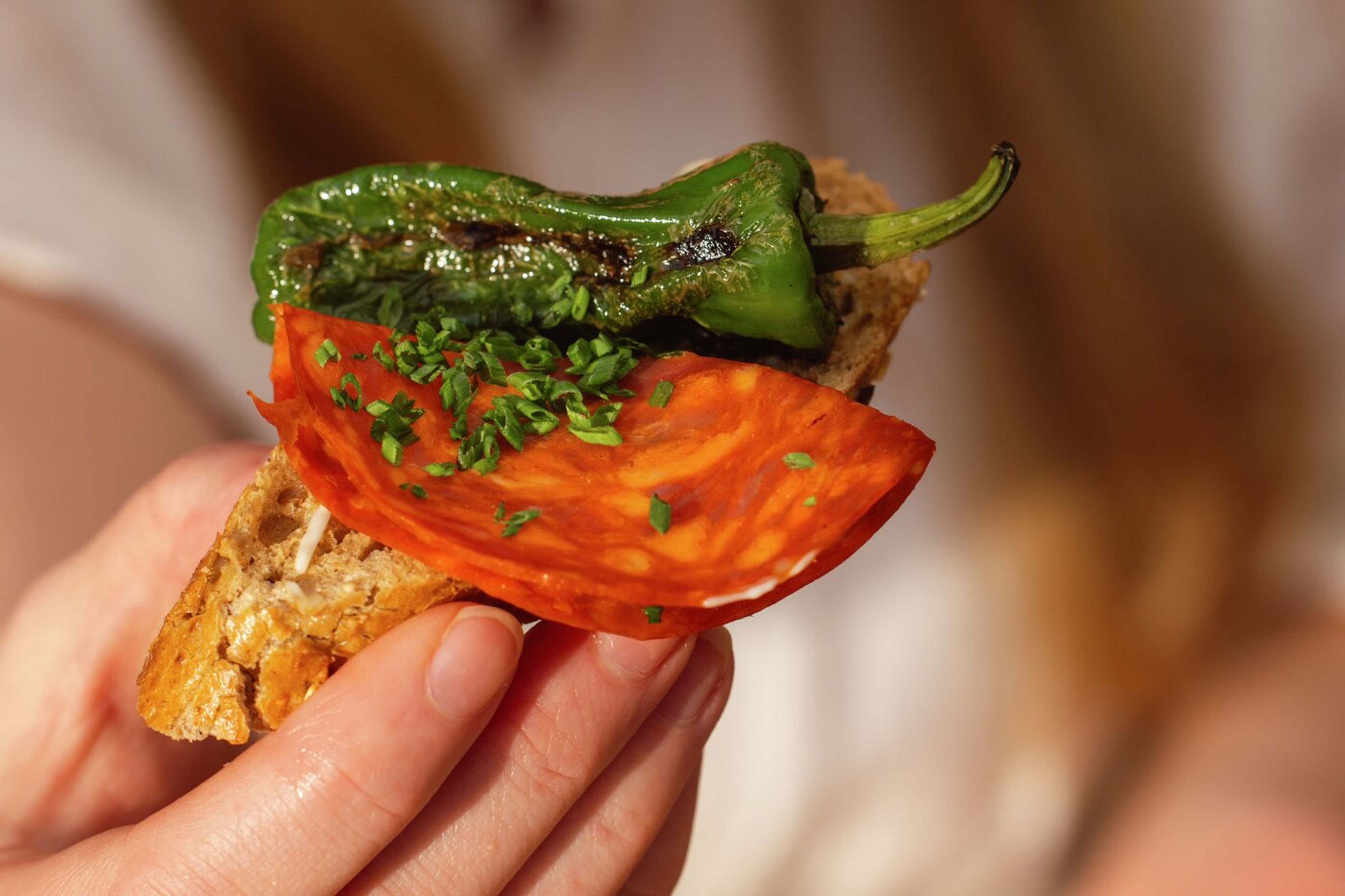 Hand som håller i en skiva bröd med chark- och grönsakstopping