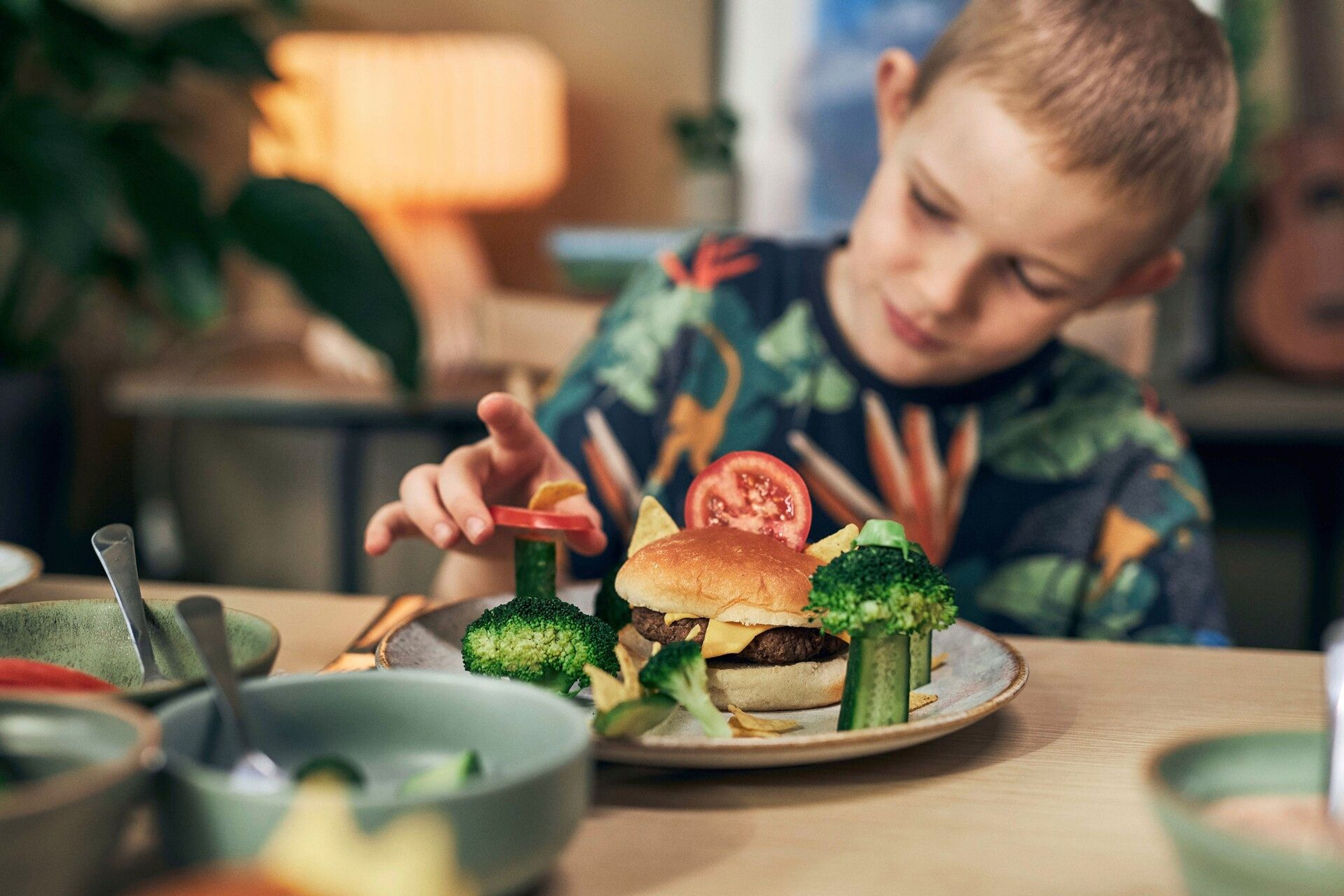 Barn som bygger sin egen lekfulla hamburgare med öron av nachochips.