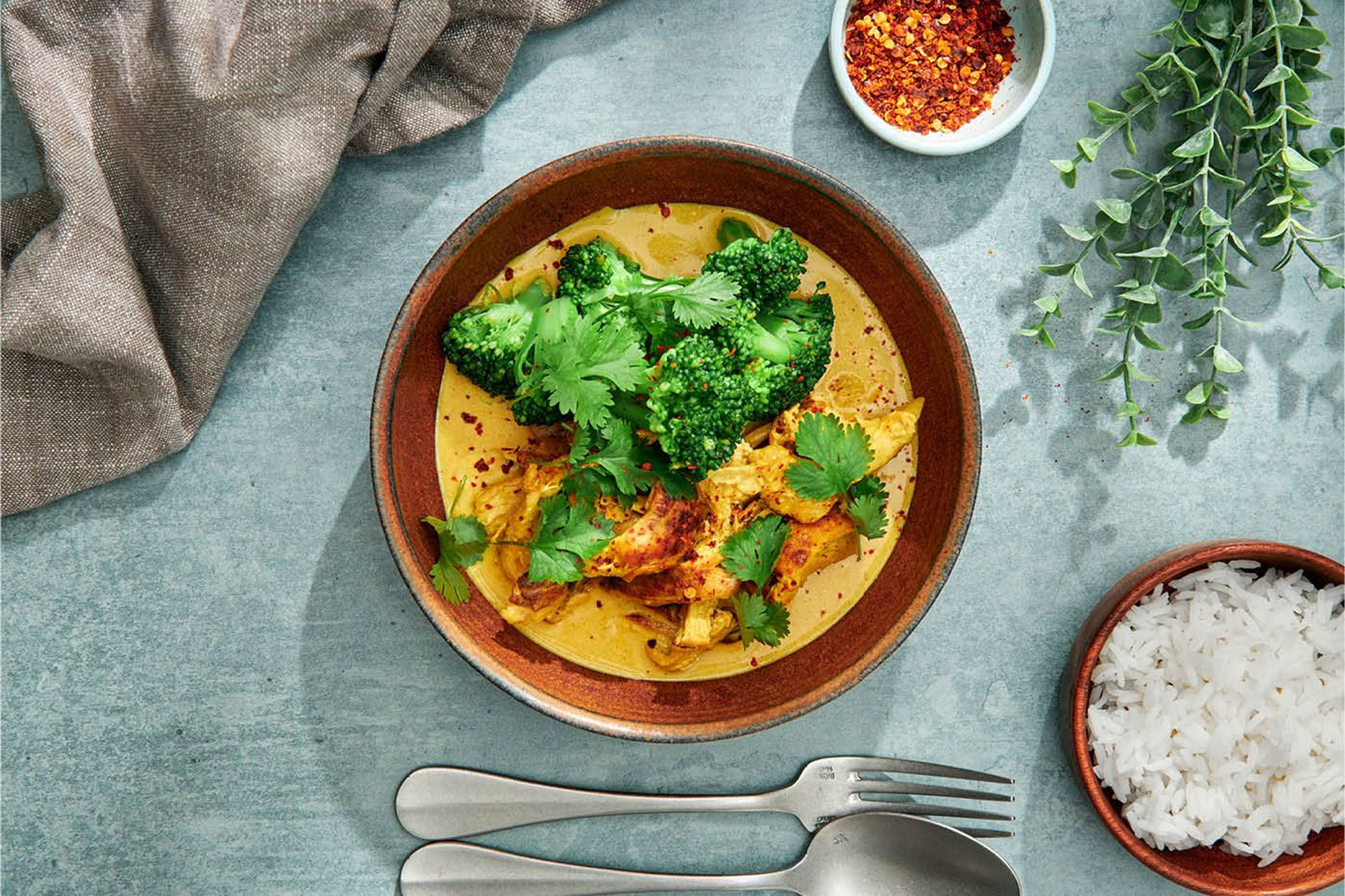 En tallrik med gul kycklingcurry toppad med broccoli