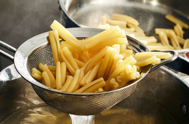 Pasta lyfts upp ur kastrull med en sil