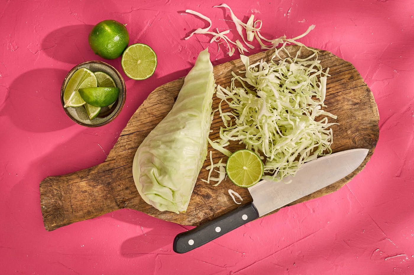 Spetskål och limefrukter på skärbräda.