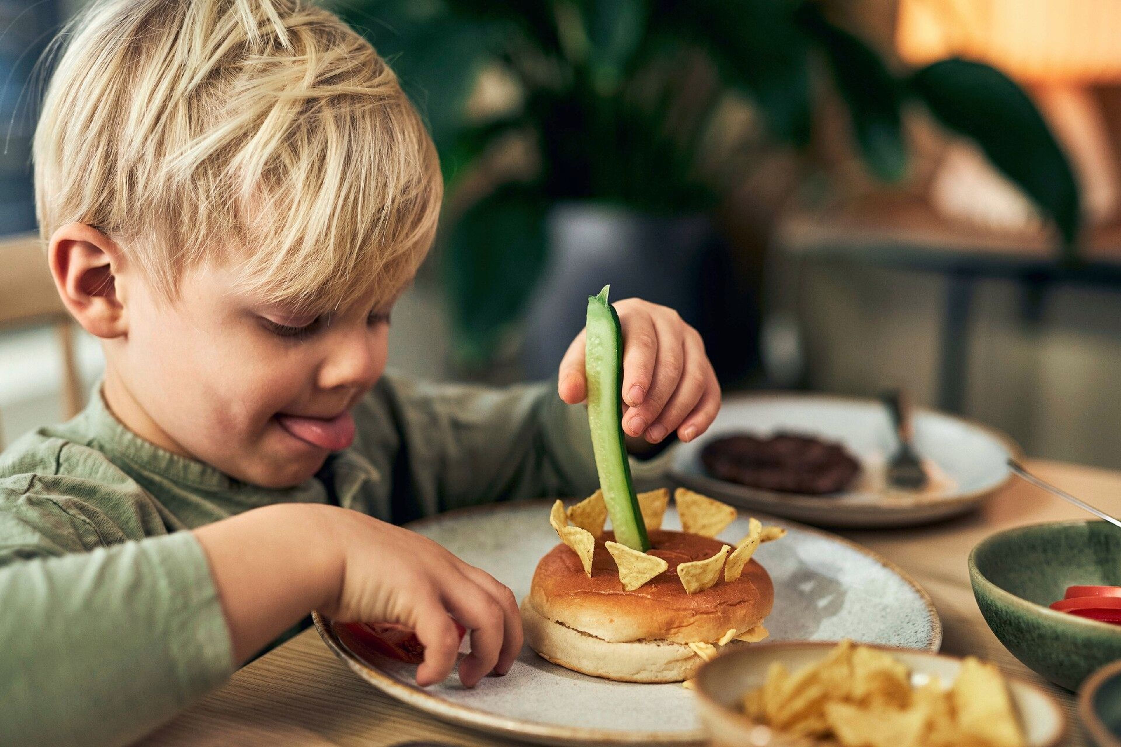 En liten kille som gör sin egen hamburgare på ett lekfullt sätt