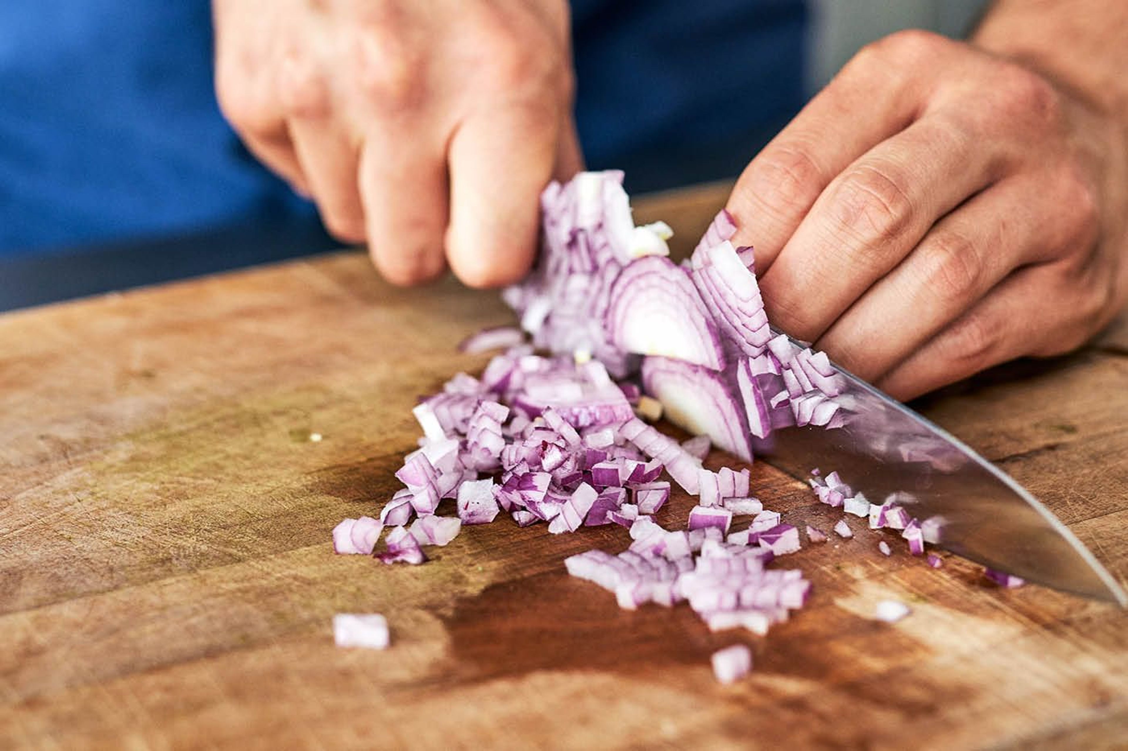 Händer som hackar lök med en vass kockkniv