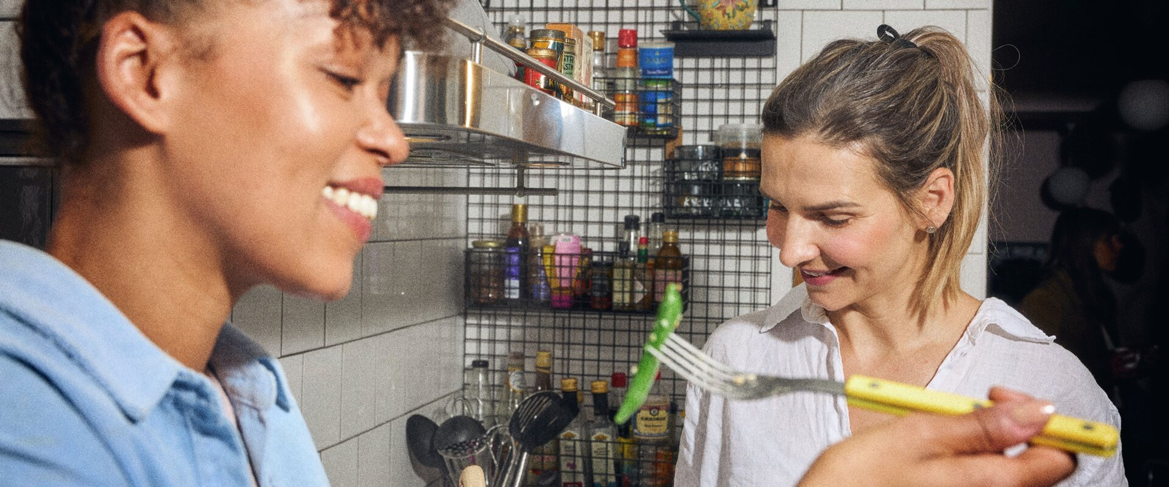 Grönsaker förbereds i ett kök, två personer i bakgrunden.
