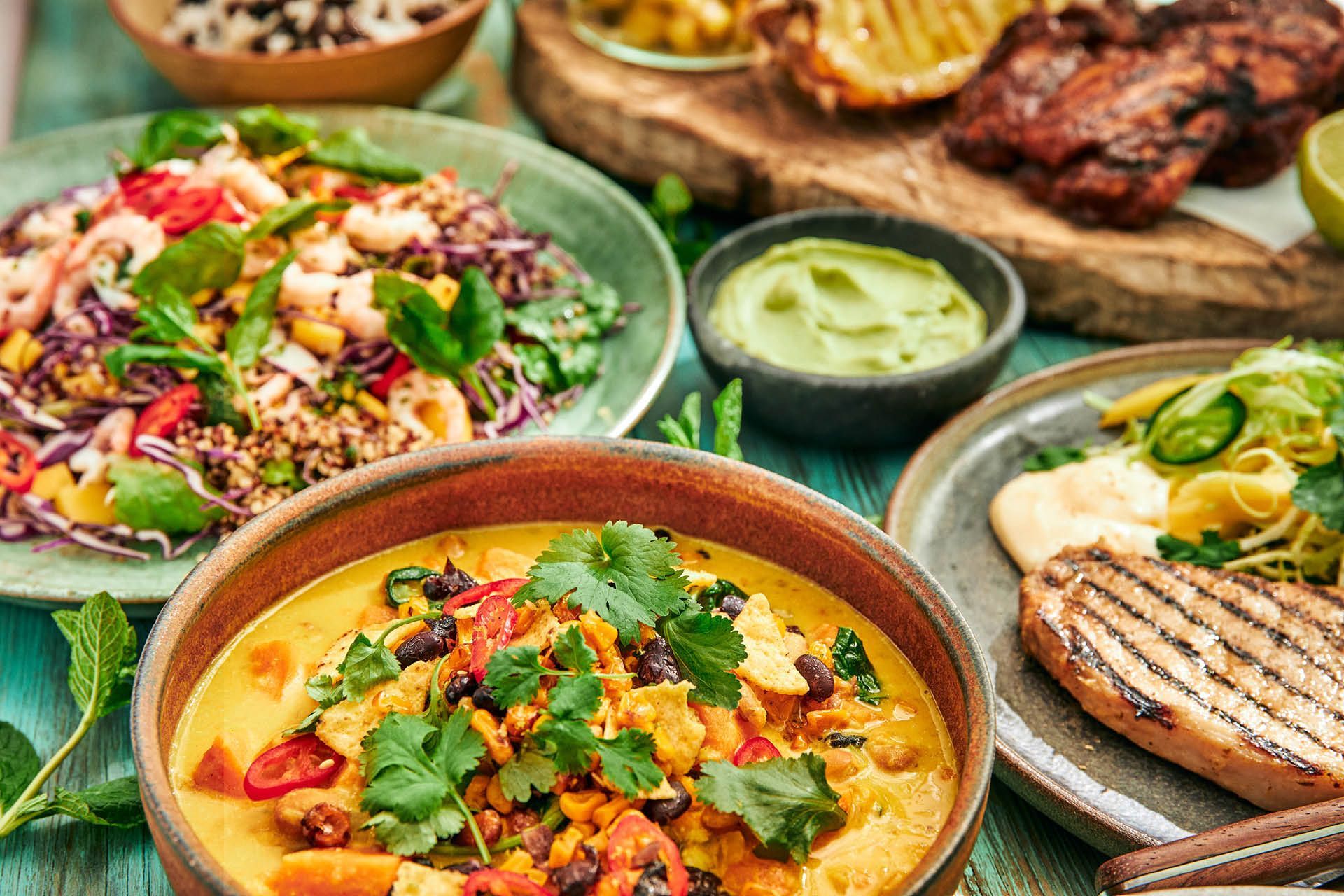 Tallrikar med karibiska rätter: räksallad, en krämig gryta, citrusmarinerad fläskkotlett