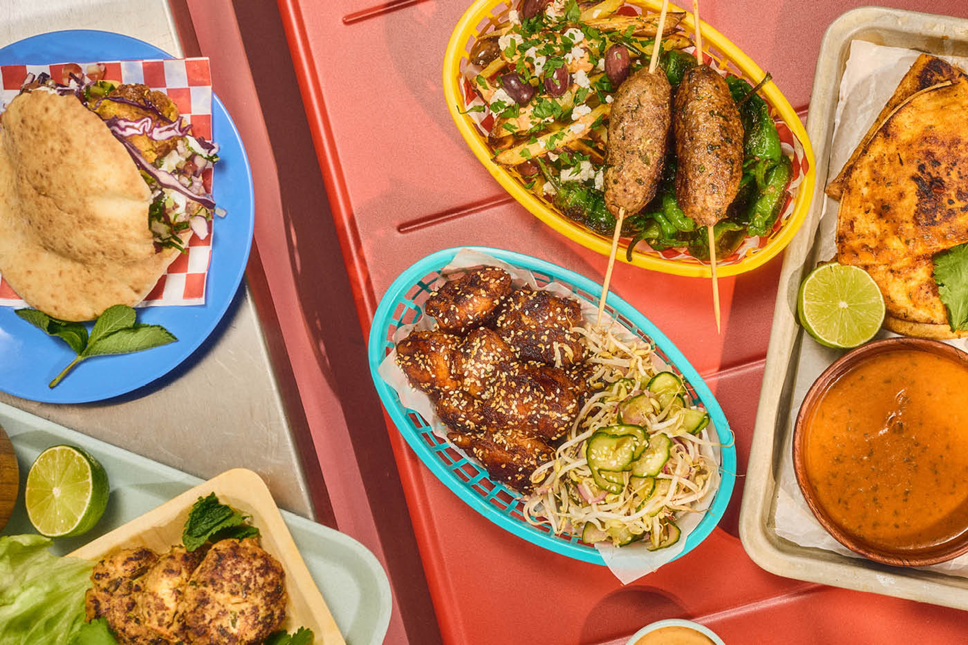 En buffé med street food-rätter och såser i skålar, korgar och på färgglada tallrikar