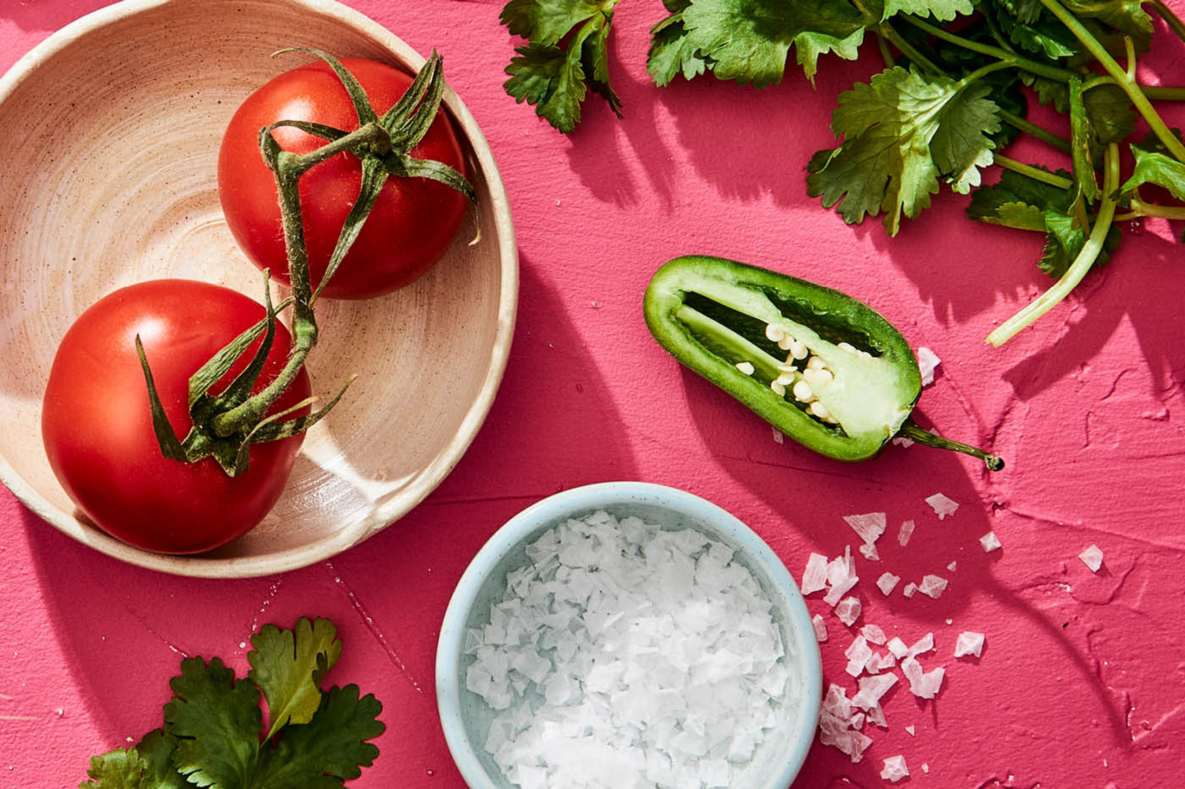 Tomat, koriander, jalapeno och salt mot rosa bakgrund