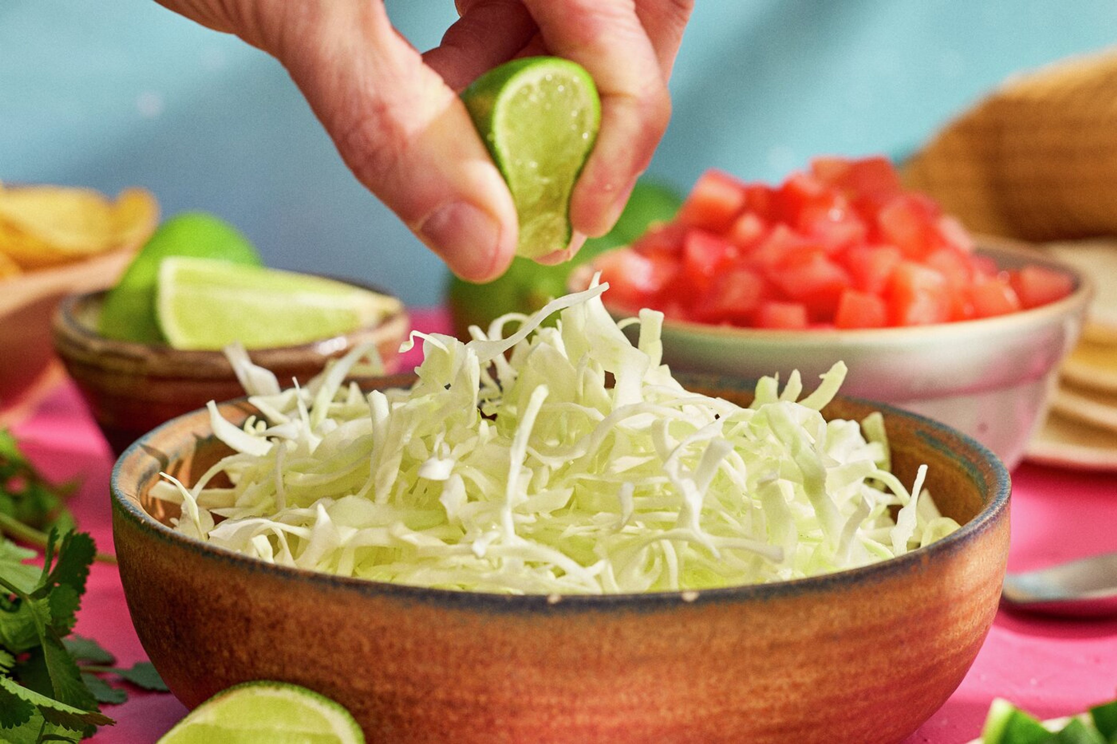 Skål med spetskål och en hand som pressar lime över