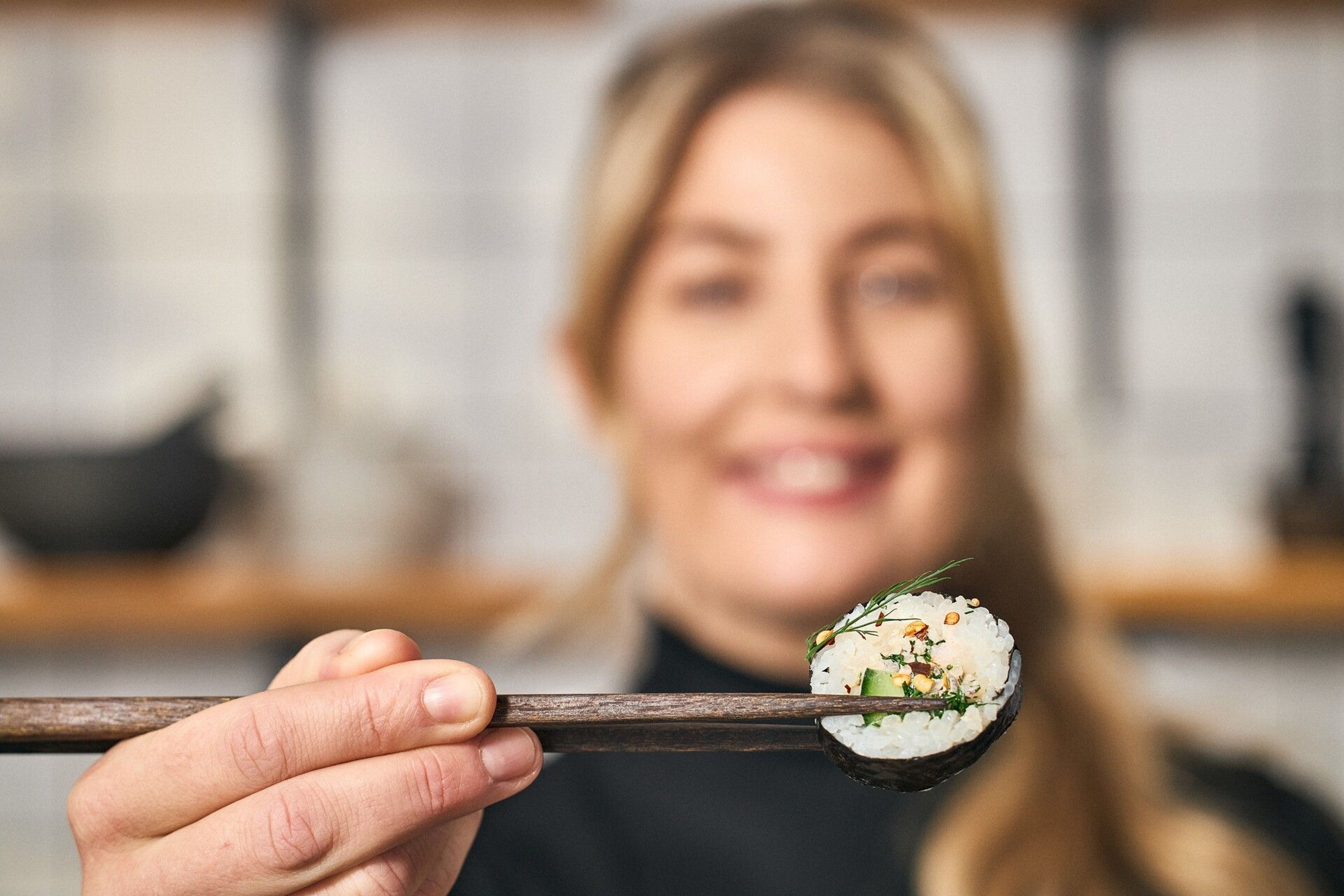 Frida Ronge håller fram en bit sushi med ätpinnar