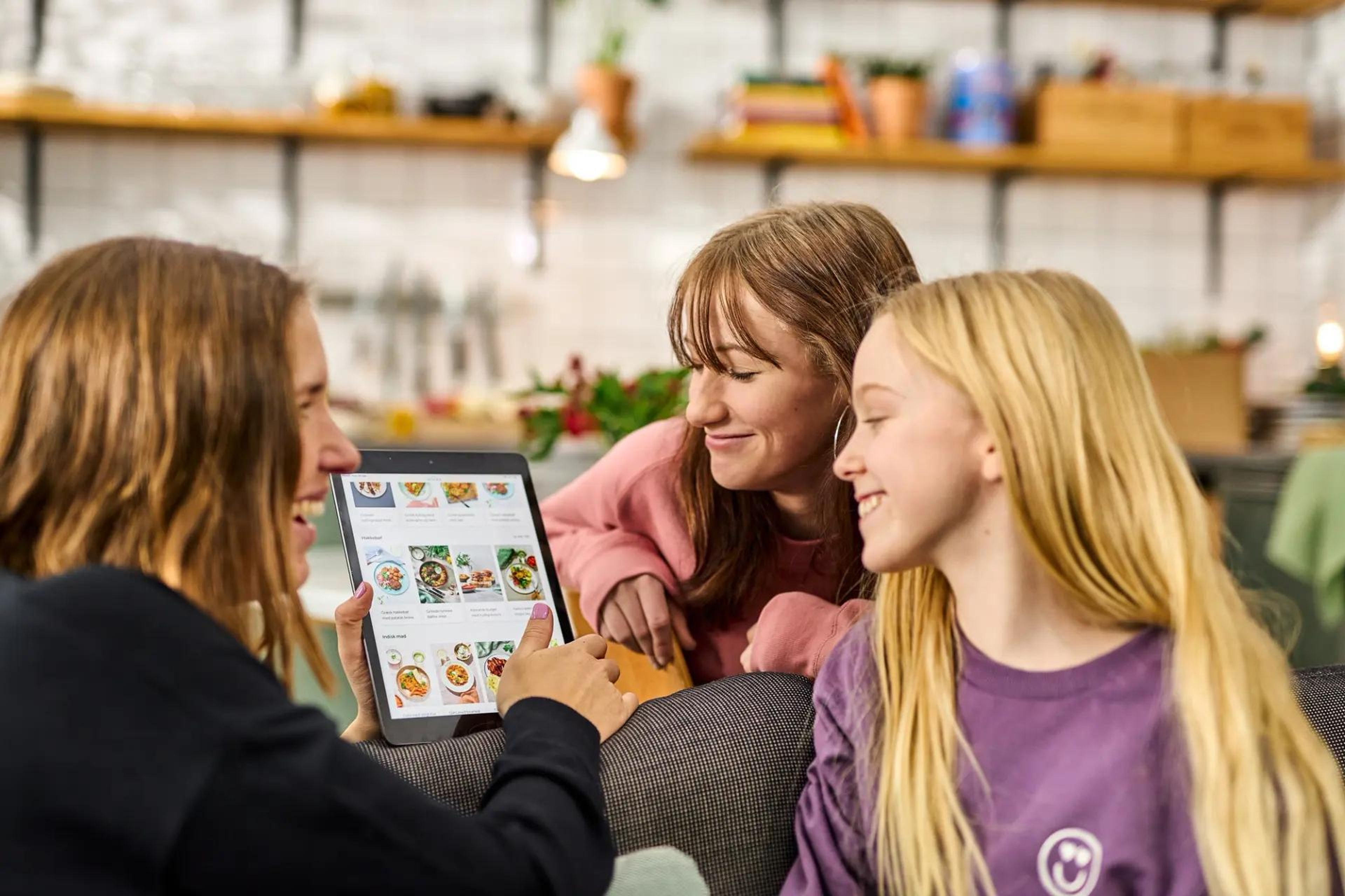 Tre tjejer i en köksmiljö beställer matkasse via Ipad