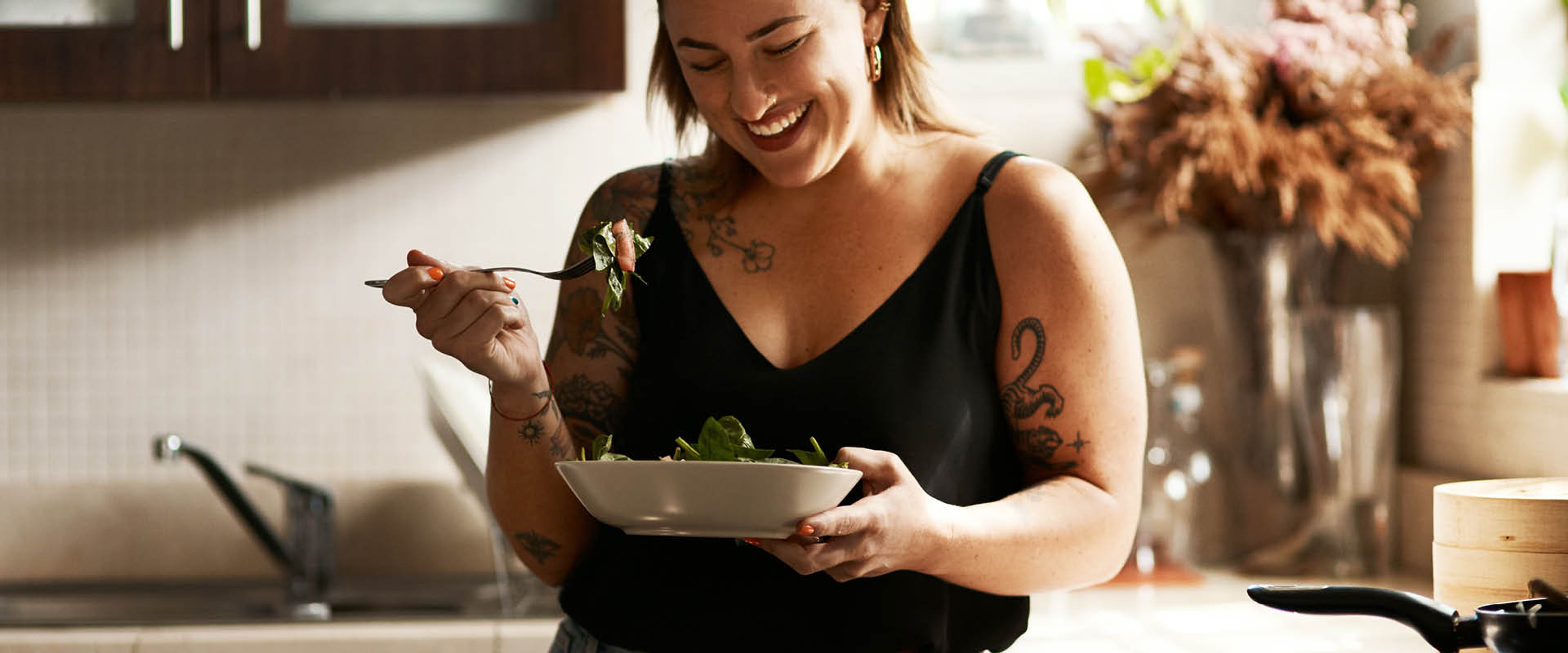 Ung kvinna äter en fräsch sallad ur en skål