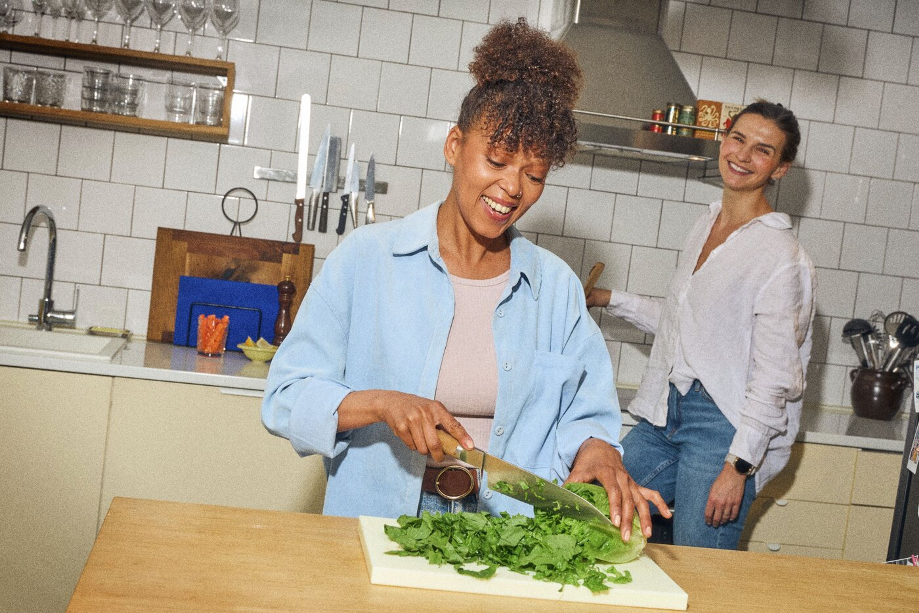 Frisk salat bliver snittet i et lyst køkken, der emmer af hygge.