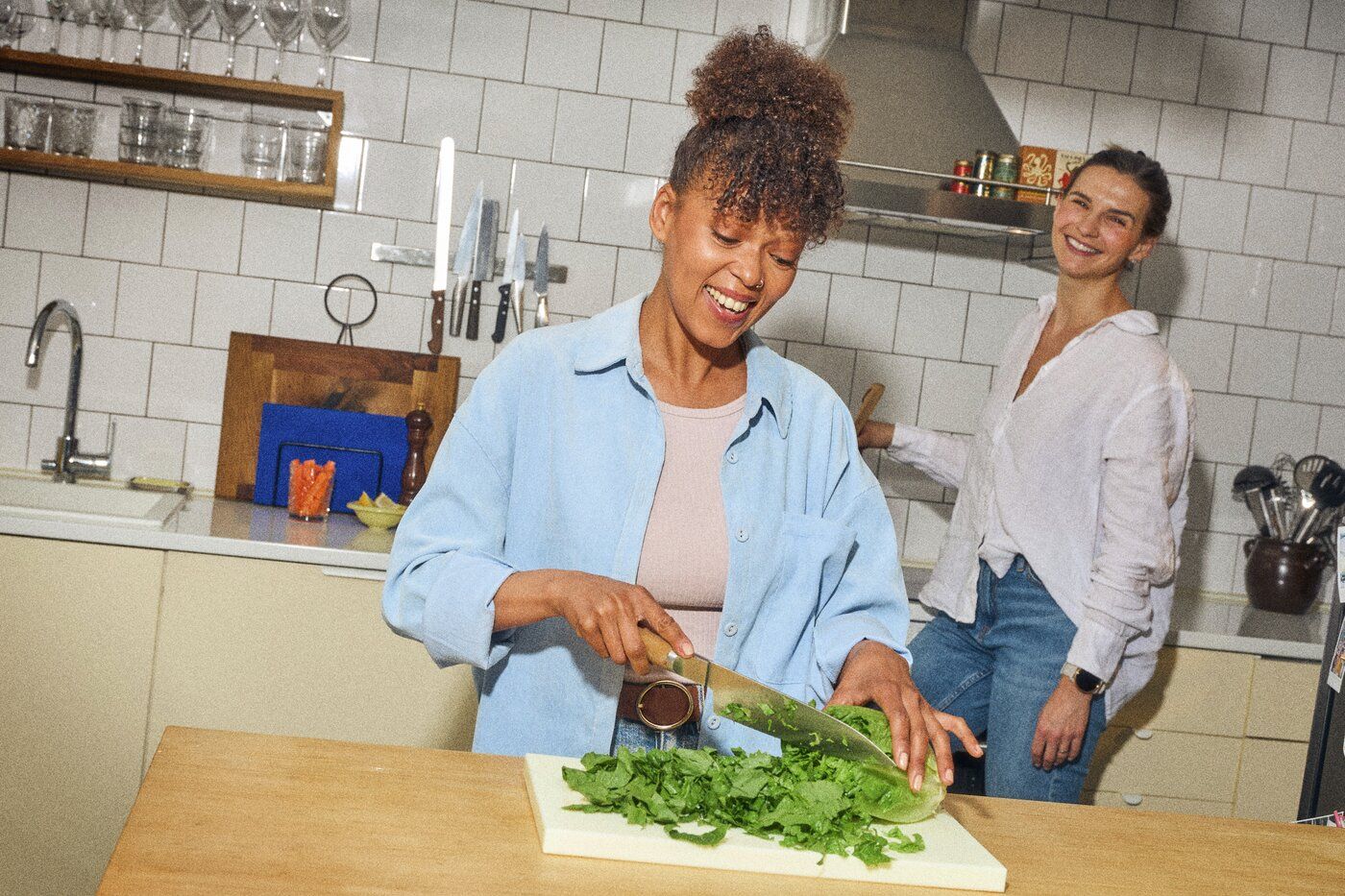 Frisk salat bliver snittet i et lyst køkken, der emmer af hygge.