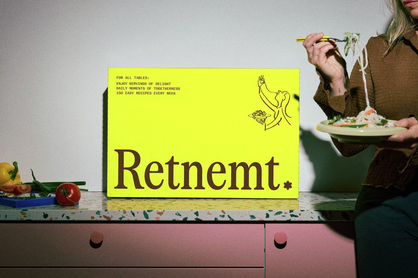 En kvinde serverer mad fra en farverig kasse med teksten "Retnemt".