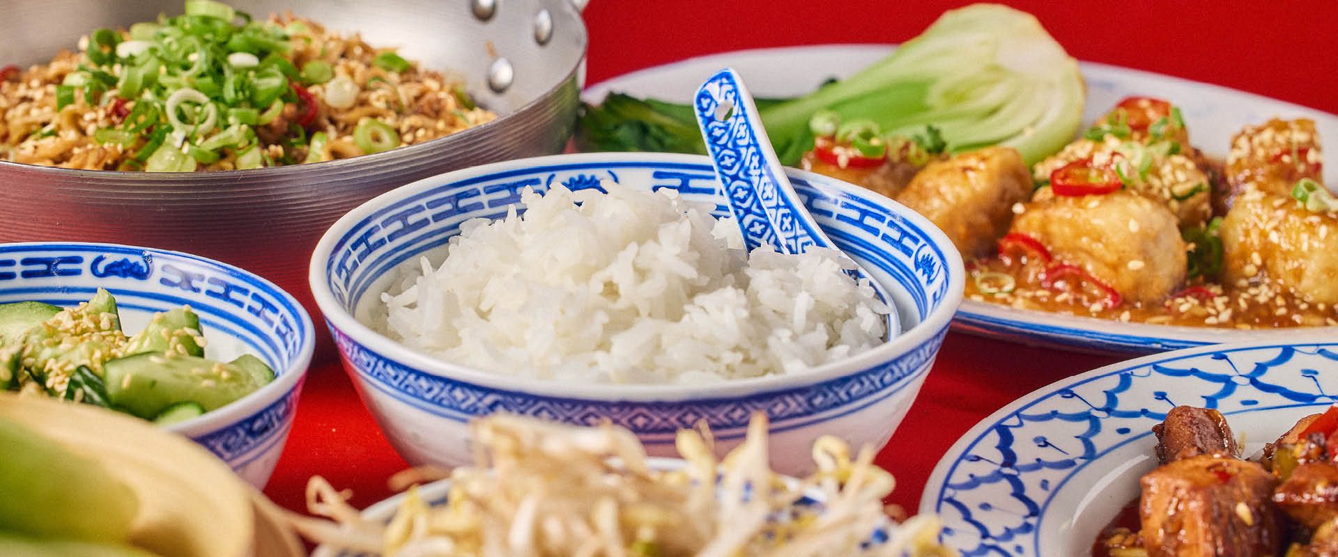 Skåle med kinesiske retter mod rød baggrund