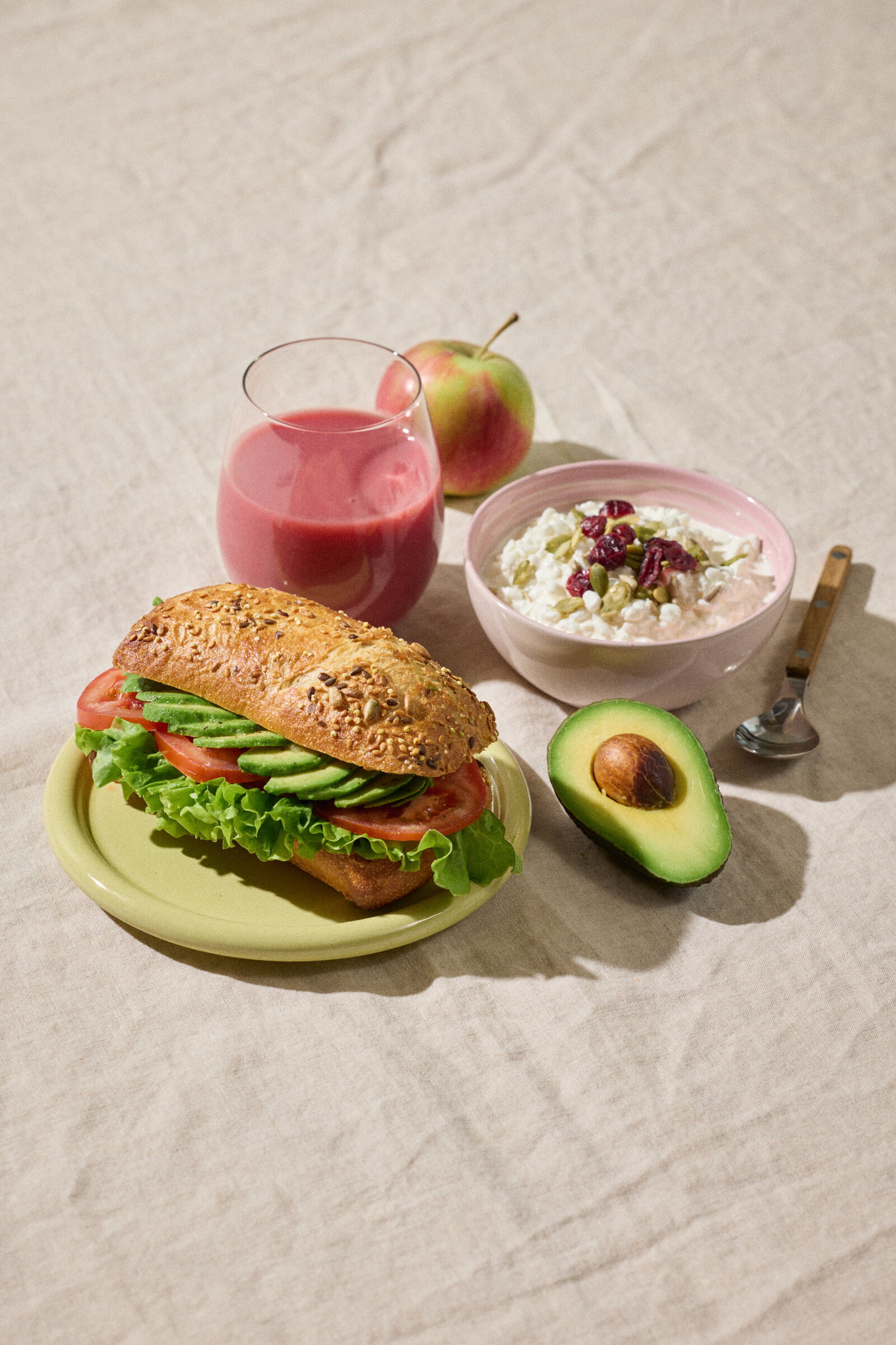 En sund frokost med sandwich, smoothie, kvark og et æble.