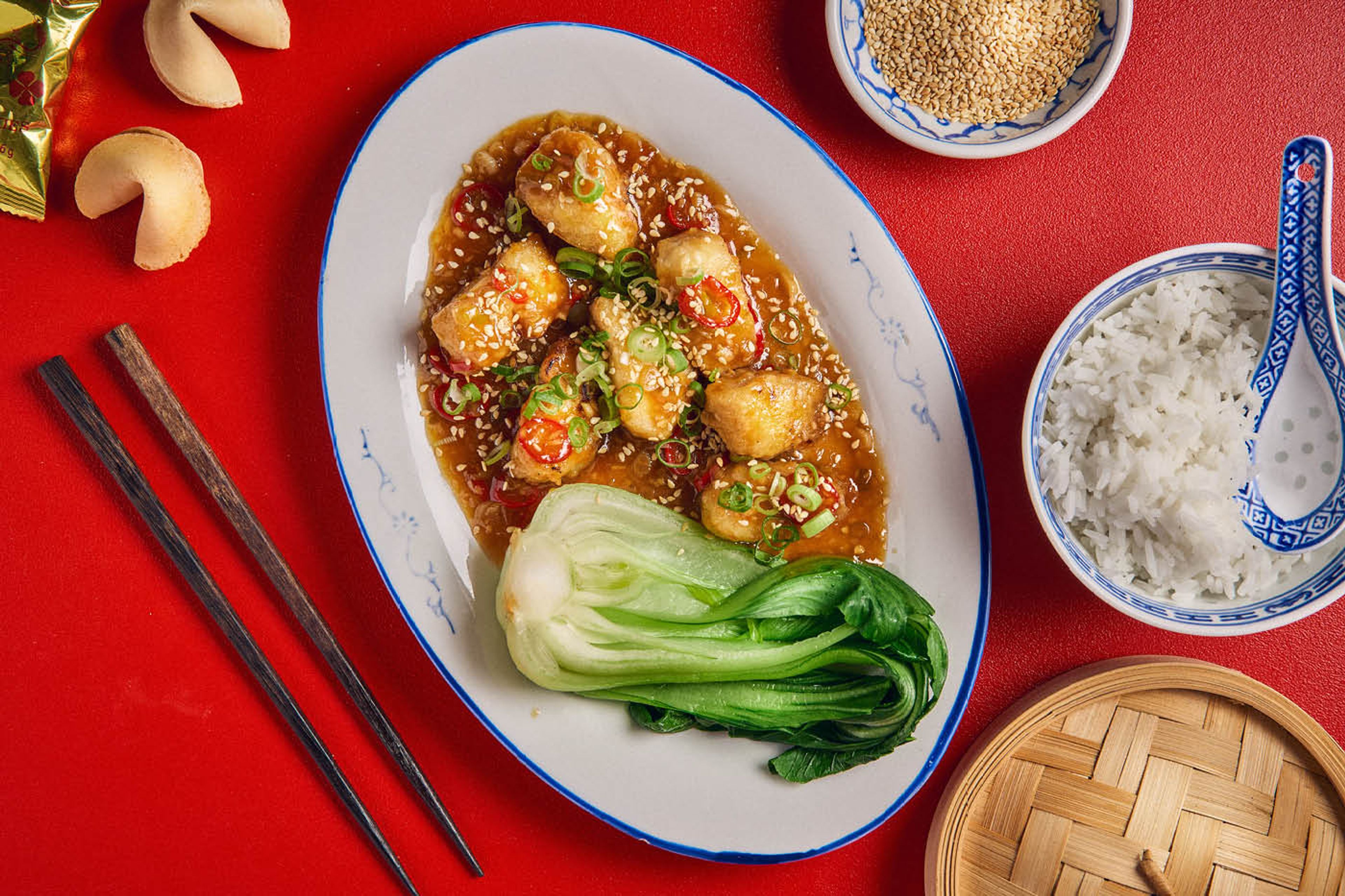 Et stort fad med fisk i sur-sød sauce med blancheret pak choy 