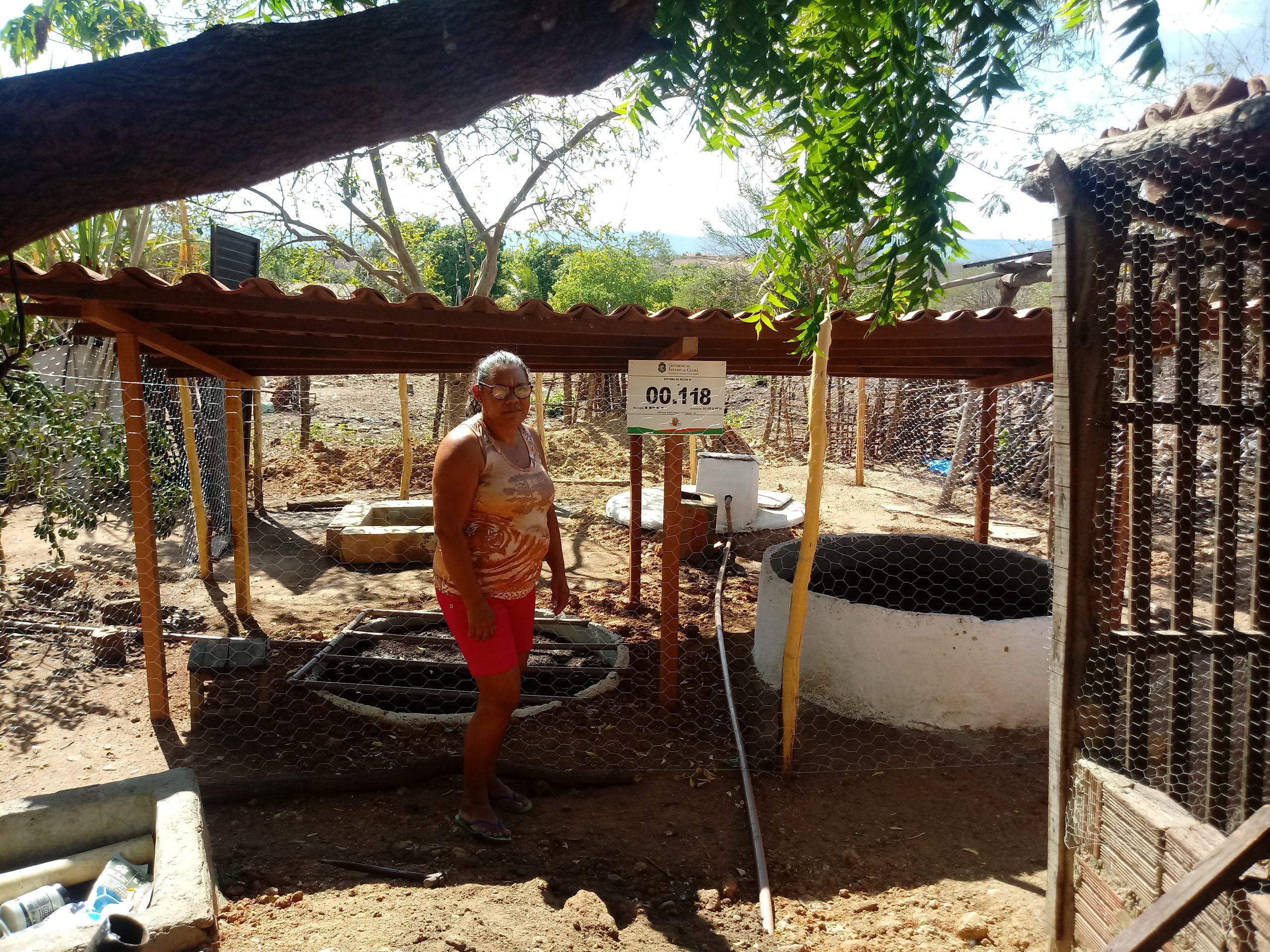 Agricultora ao lado do filtro do sistema de reúso